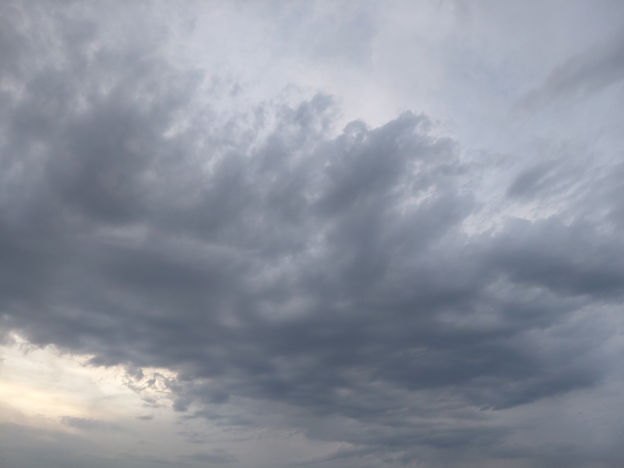 A panoramic view of a cloudy sky over Verhnyaya Podstyopnovka, Russia, captures the atmospheric conditions with a dominant presence of grey and white cumulonimbus clouds. The sky is overcast, suggesting a possibility of rain or a storm. The lighting is diffused, typical of a cloudy day. There are no visible people, animals, or man-made structures in the frame, focusing solely on the natural expanse of the sky and its cloud formations.