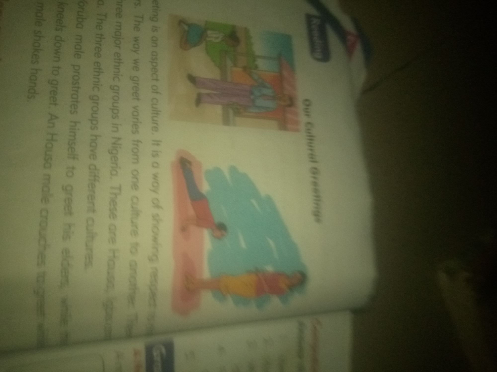 The image displays a page from a book, with text on the left and illustrations on the right. The text discusses greeting customs, mentioning that "Greeting is an aspect of culture. It is a way of showing respect to others. The way we greet varies from one culture to another. The three major ethnic groups in Nigeria. These are Hausa, Igbo, and Yoruba male prostrates himself to greet his elders, while a male shakes hands."
The illustrations depict different greeting scenarios. One illustration shows two figures in traditional attire, one standing and the other kneeling. The second illustration depicts two figures, one in a red and yellow outfit and the other in red, seemingly in a resting or greeting posture on a blue background.
The provided context mentions the city of Jauro Yinu, Nigeria, and while the text discusses Nigerian ethnic groups and greeting customs, there is no direct visual information in the image that can confirm or deny the presence of Jauro Yinu. The image primarily focuses on the cultural aspect of greetings as presented in a book.