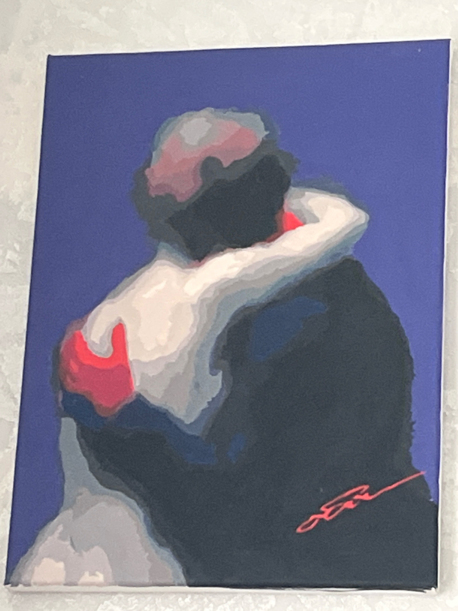 The image displays a painting of two figures embracing, with a dark blue background. The figures are rendered in a stylized, somewhat abstract manner, with a prominent use of soft shading and limited color palette. The figure on the left appears to be wearing a white garment, while the figure on the right is predominantly dark. Red accents are visible on the left figure's shoulder and a signature in red is present on the right figure's torso. The painting is on canvas and appears to be framed or has a white border. The background texture suggests it might be a wall or textured surface. There are no identifiable landmarks or contextual elements within the painting to suggest a specific location in Шевырялово, Russia.