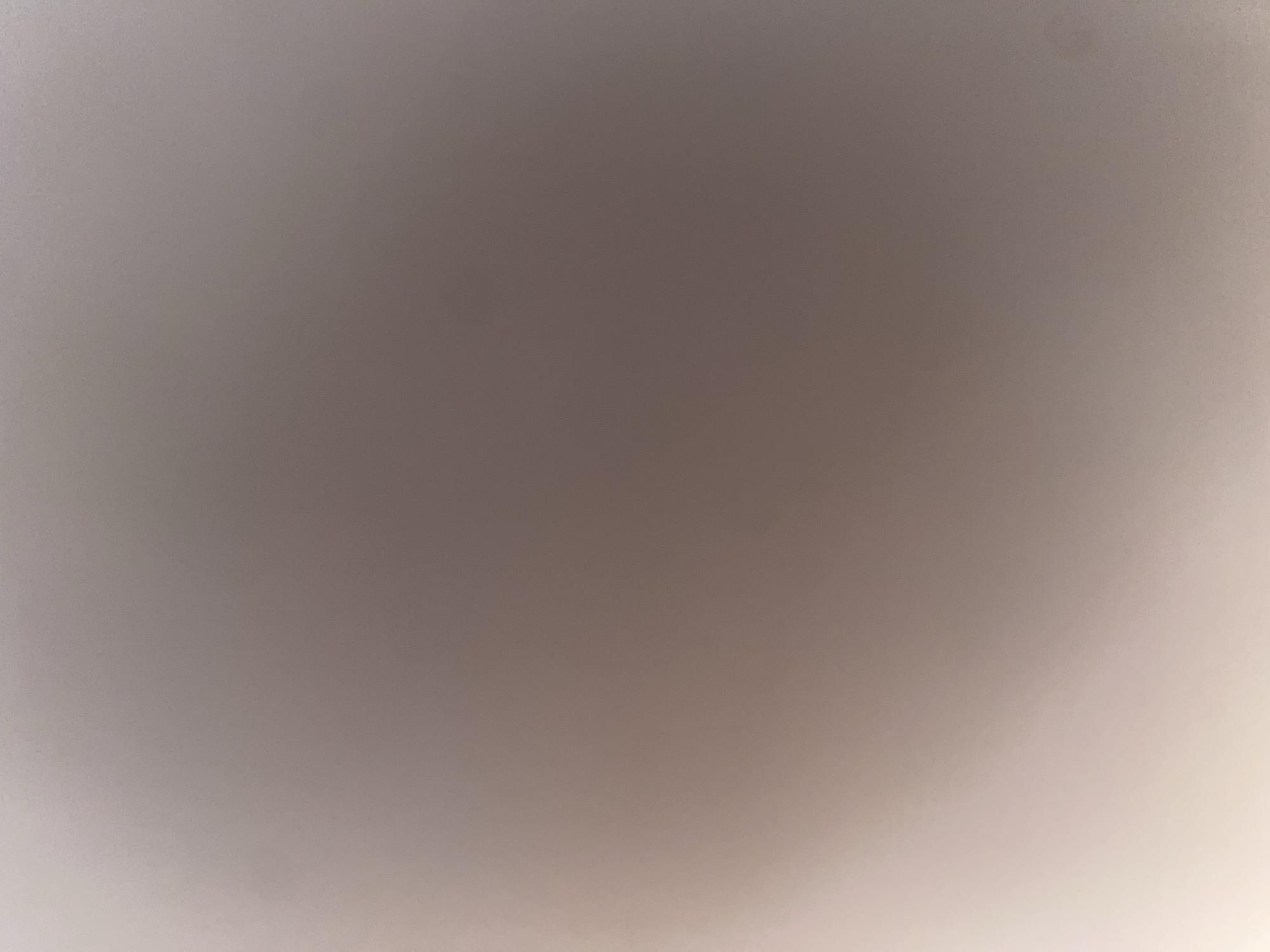 The image is a softly lit, out-of-focus photograph with a gradient of light and dark tones. The dominant colors are muted grays, browns, and off-whites. There are no discernible subjects, objects, actions, or interactions visible in the image. The scene appears to be a blank or featureless surface, possibly a wall or ceiling, with subtle variations in light intensity creating a sense of depth. There is no information within the image itself that can be used to determine its location, including in the city of Ablanitsa, Bulgaria.