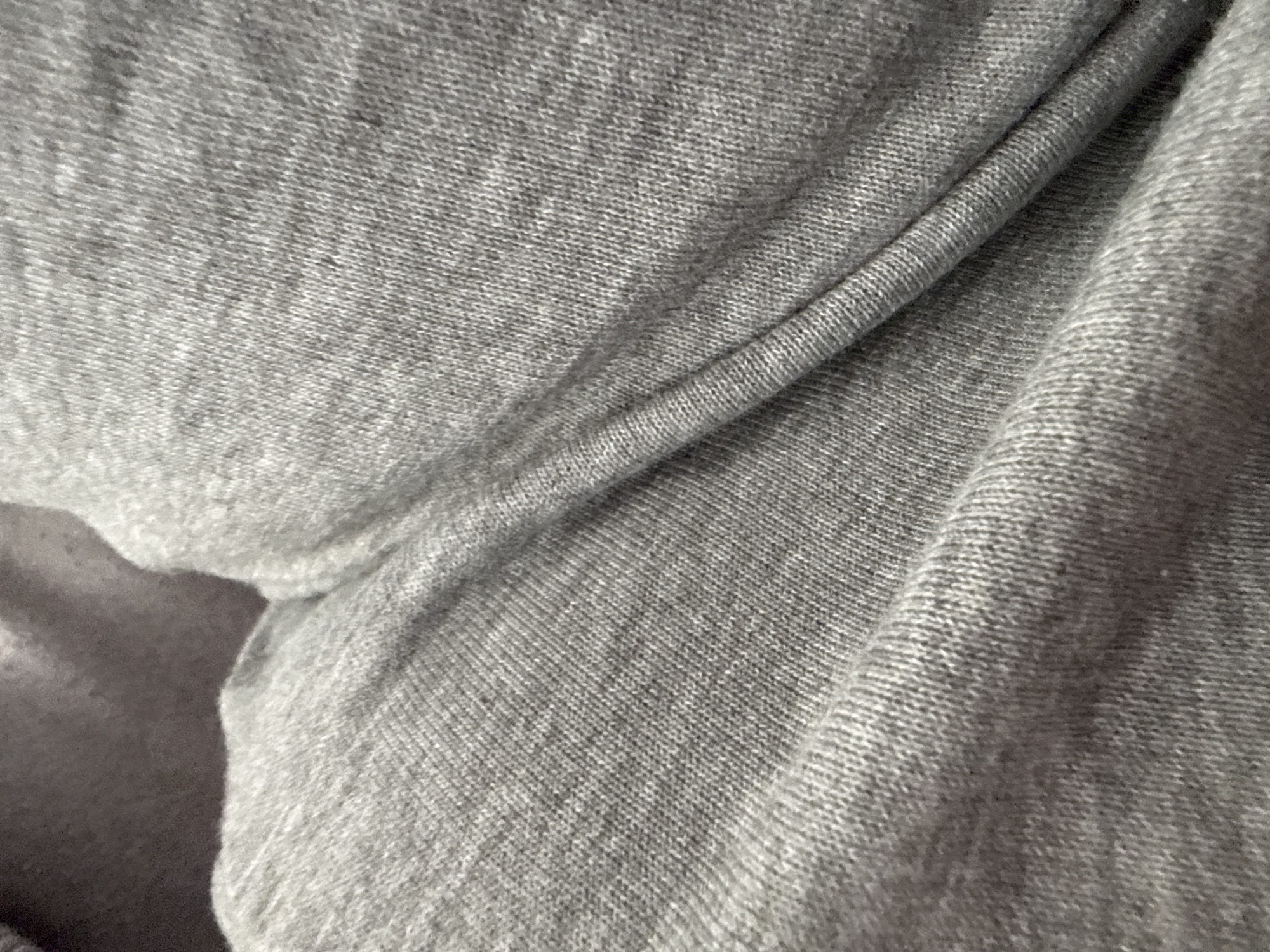 A close-up photograph depicts gray, loosely woven fabric draped in folds. No people or location are discernible.