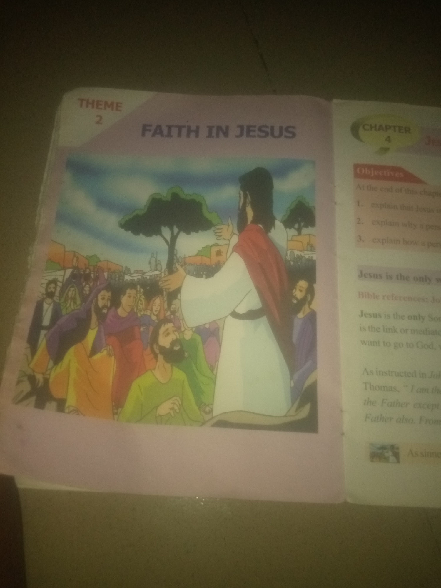 The image shows an open book with text and an illustration. The left page features a pink background with a title "THEME 2 FAITH IN JESUS". Below this title is an illustration depicting Jesus speaking to a crowd of people. Jesus, dressed in a white robe and red cloak, stands with his hand raised. The crowd, composed of individuals in colorful robes, is gathered around him. The right page has a "CHAPTER 4" heading and a list of objectives, including "1. explain that Jesus is...", "2. explain why a pers...", and "3. explain how a pers...". Further down, there is text about "Jesus is the only w" and "Bible references: Jo...". The lower part of the right page includes the phrase "As instructed in Jo...", followed by quoted text, and "the Father also. From" and "As sinne". The image lacks any discernible elements that would indicate a specific location in Jauro Yinu, Nigeria, or any other city.