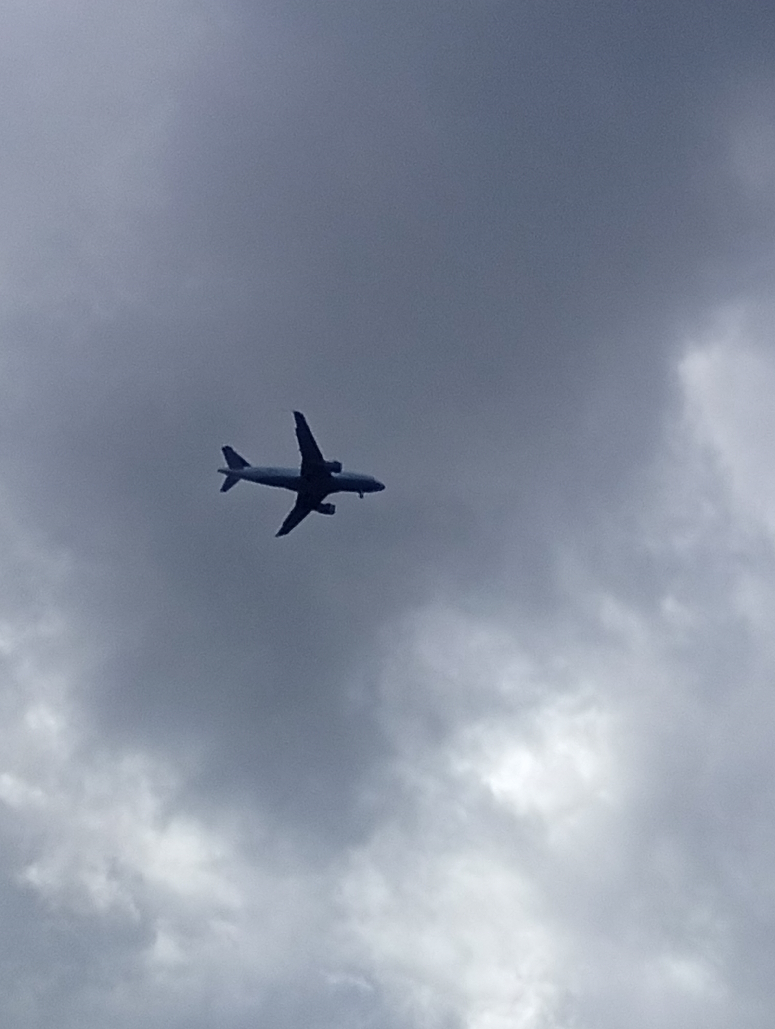 An airplane is silhouetted against a cloudy, gray sky. The aircraft appears to be a passenger jet, with its wings extended and engines visible. The image does not depict any identifiable landmarks or features of Wrocław, Poland, and there are no people visible.