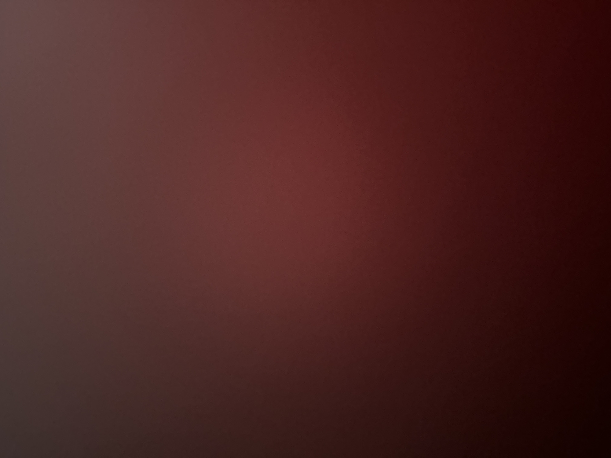 The image is a dark, reddish-brown abstract background. It appears to be a gradient of color, with the top left being a lighter shade and the bottom right being a darker, more intense shade of red. There are no discernible objects, people, or specific locations visible. The lighting is dim, creating a moody and atmospheric effect.