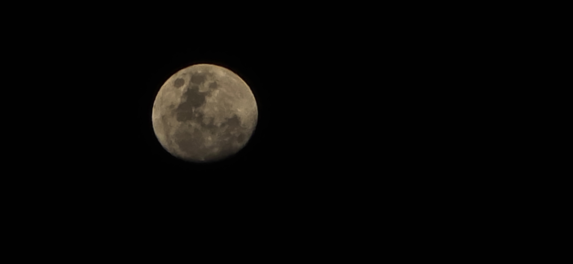 The image shows a near-full moon against a black sky. Details of the moon's surface are visible, including craters and maria. The location is unknown, therefore it is not possible to confirm if this image was taken from the city of Huesca, Spain.