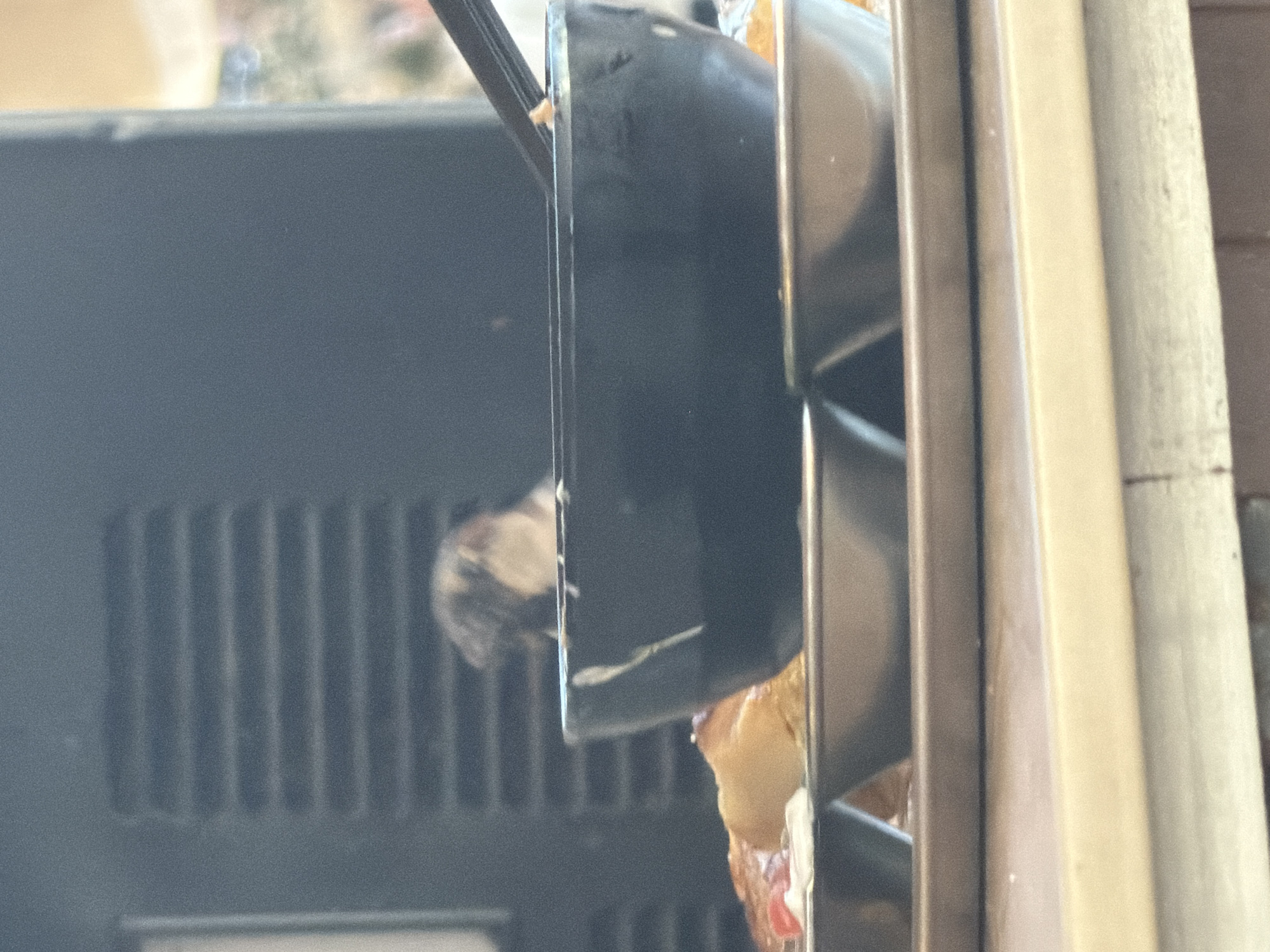 A blurred view of an object (possibly food) inside what appears to be an oven or similar appliance. Part of a vent system on the left side of the appliance and adjacent panels of an oven door and frame are visible. Due to the extreme close-up and lack of context, it is not possible to ascertain the location in Tel-Aviv, Israel, or any other details regarding people, actions, or interactions.