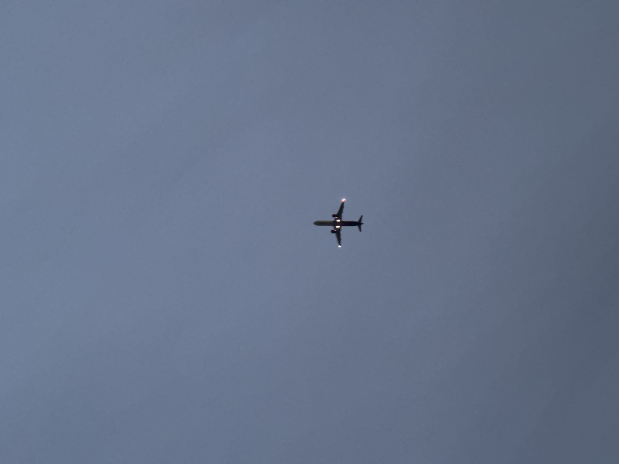 A solitary aircraft is positioned centrally against an overcast gray sky. No buildings, landscapes, or any other identifying features are visible in the frame. As such, the location is impossible to ascertain.