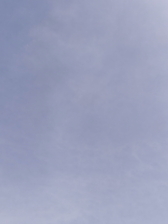 The image displays a uniform, light blue-grey expanse, indicative of an overcast or hazy sky. Subtle, diffuse lighter variations are present across the frame, suggesting thin, indistinct cloud cover or atmospheric haze. No discernible objects, people, structures, or ground features are visible within the frame. The image provides no contextual information to determine a specific location within Dalton-in-Furness, United Kingdom, or any other geographical area. No actions or interactions are depicted.