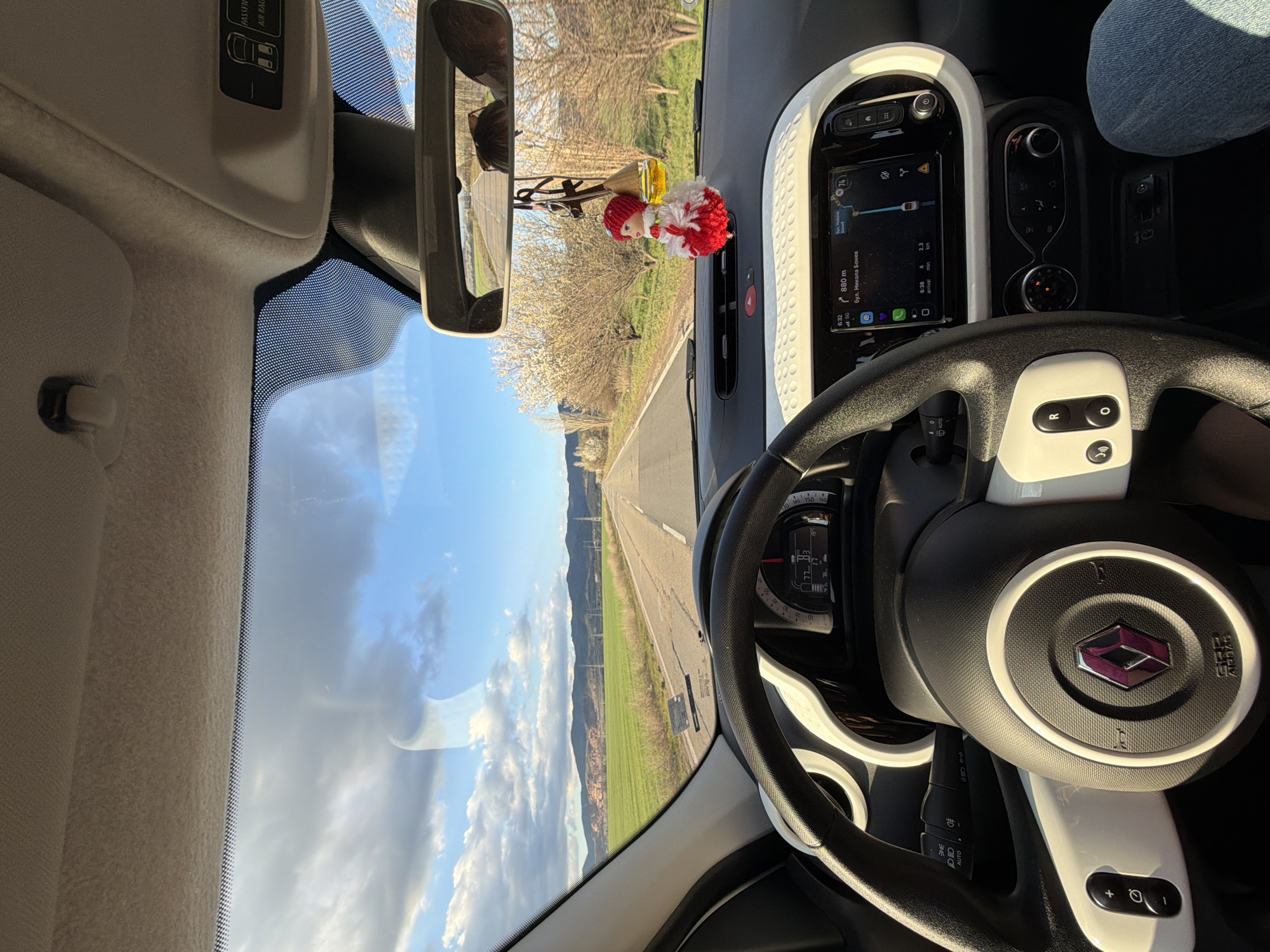 The image, taken from inside a car, shows the dashboard and steering wheel of a Renault Twingo. A road stretches into the distance as seen through the windshield and rearview mirror. The navigation system shows that the car is 880 meters from "бул. Никола Бонев," a street in Buhovo, Bulgaria. The time is 6:32, and the estimated time of arrival is 6:36, covering a distance of 2.3 km. A small decorative doll hangs from the rearview mirror.