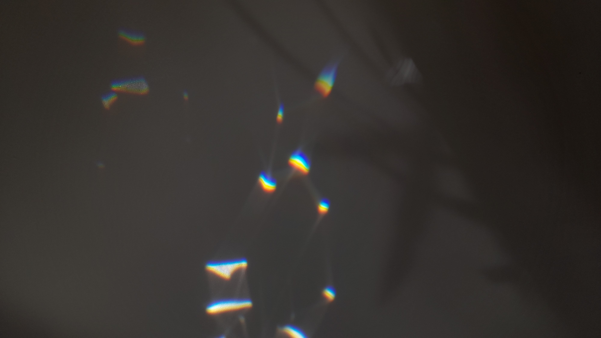 The image depicts a gray wall with scattered prismatic reflections of light, creating rainbow-like patterns. The setting is indoors. There are no people or distinct objects. The location in the city of Saint Petersburg, Russia is not able to be determined by the image.