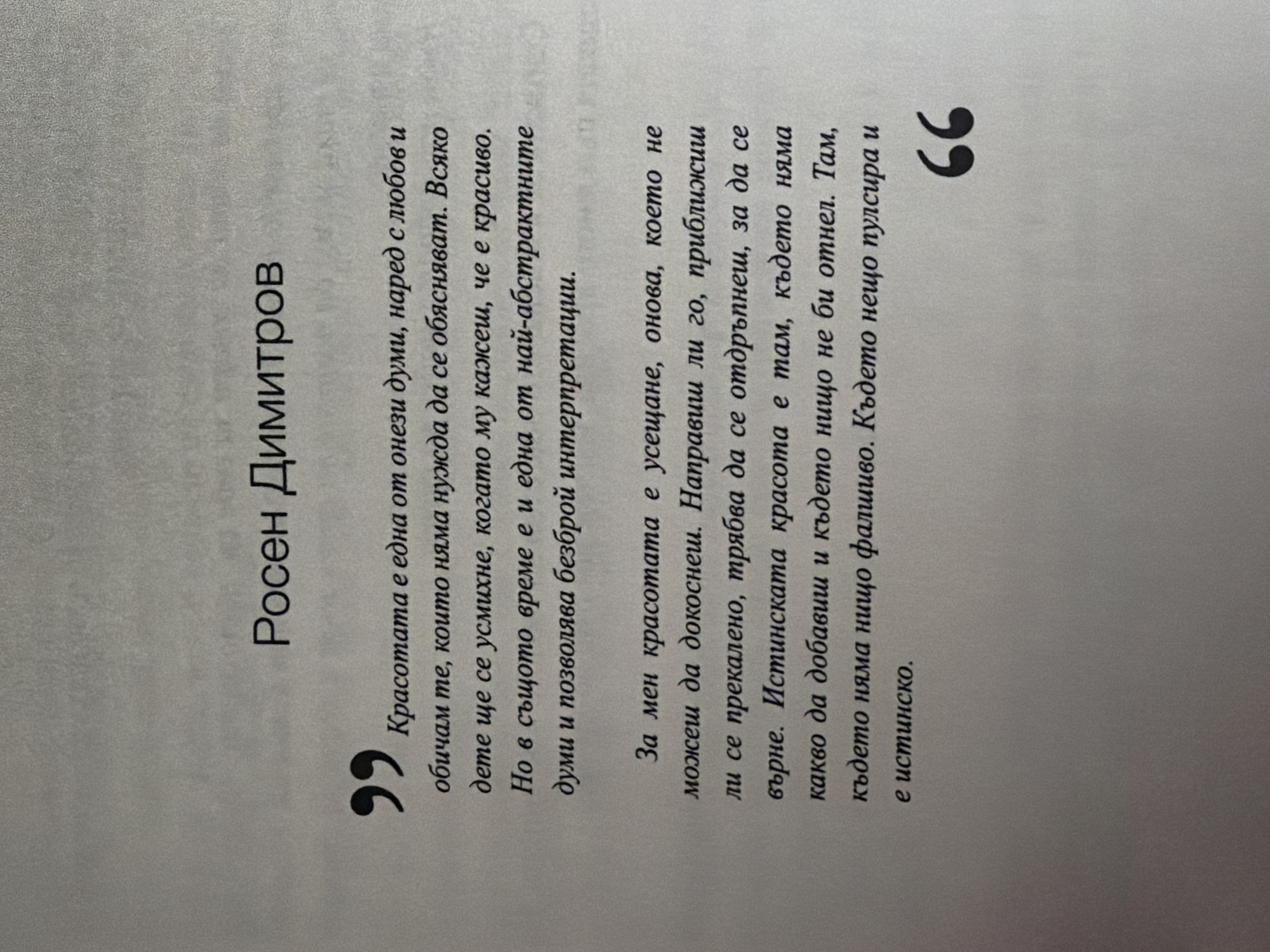 The image shows a page from a book with text in Bulgarian. At the top, centered, is the name "Росен Димитров" (Rosen Dimitrov). Below this, a quote is presented, enclosed by quotation marks. The quote begins with "Красотата е една от онези думи, наред с любов и обичам те, които няма нужда да се обясняват. Всяко дете ще се усмихне, когато му кажеш, че е красиво. Но в същото време е и една от най-абстрактните думи и позволява безброй интерпретации." This translates to "Beauty is one of those words, along with love and I love you, that need no explanation. Every child will smile when you tell them they are beautiful. But at the same time, it is one of the most abstract words and allows for countless interpretations."
The second part of the quote reads: "За мен красотата е усещане, онова, което не можеш да докоснеш. Направиш ли го, приближиш ли се прекалено, трябва да се отдръпнеш, за да се върне. Истинската красота е там, където няма какво да добавиш и където нищо не би отнел. Там, където няма нищо фаливо. Където нещо пулсира и е истинско." This translates to "For me, beauty is a feeling, one that you cannot touch. If you do, if you get too close, you have to step back for it to return. True beauty is where there is nothing to add and nothing to take away. Where there is nothing false. Where something pulses and is real."
The bottom right of the page features a large, stylized closing quotation mark. The background is a plain, lightly textured gray. There is no indication of the city of Pazardzhik, Bulgaria, or any environmental details beyond the book page itself.