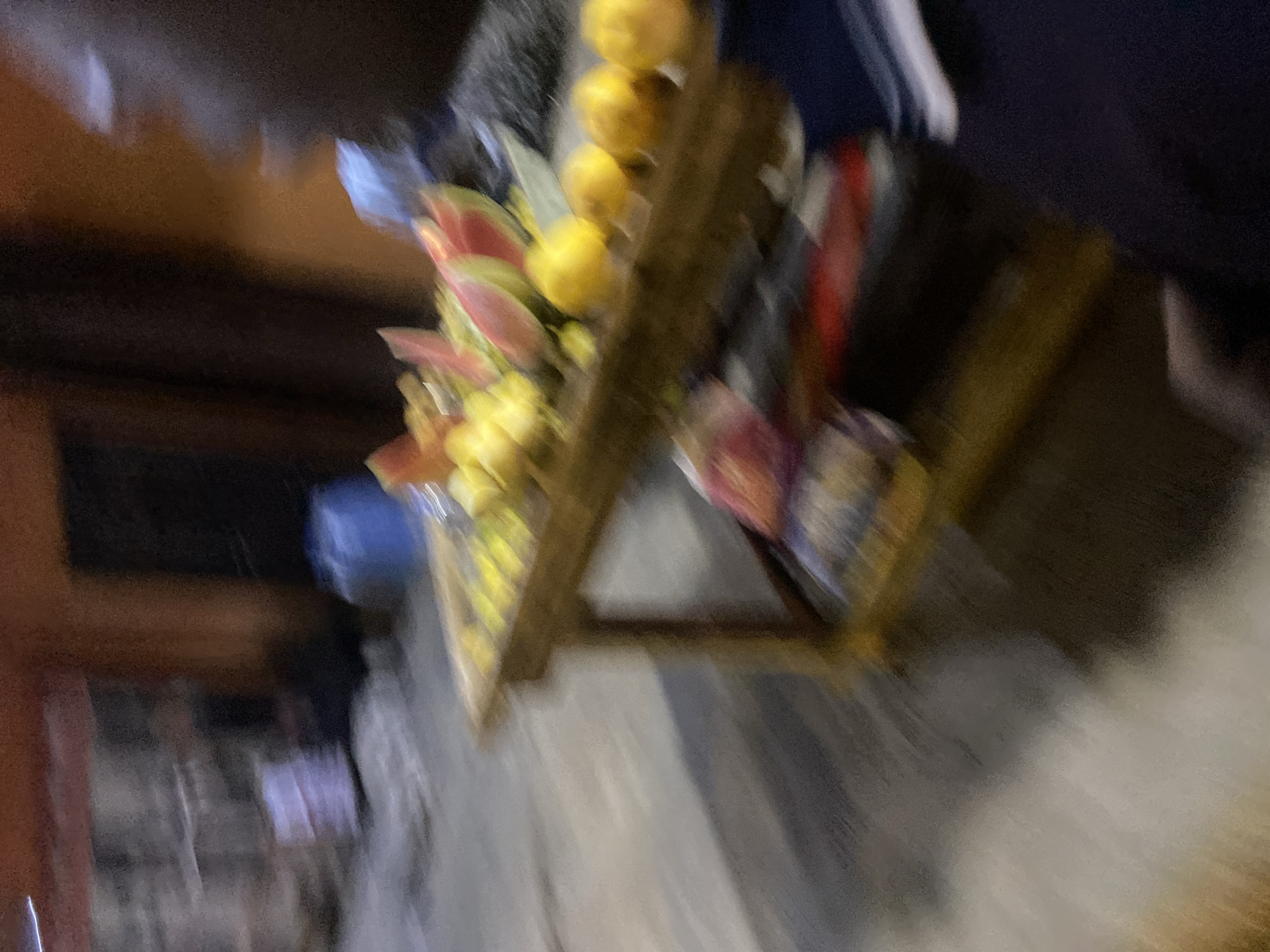 A blurred image shows a street vendor's stall in Lagos, Nigeria. The stall displays a variety of items, including oranges, flowers, and newspapers. The vendor is not clearly visible. The environment appears to be a busy street.