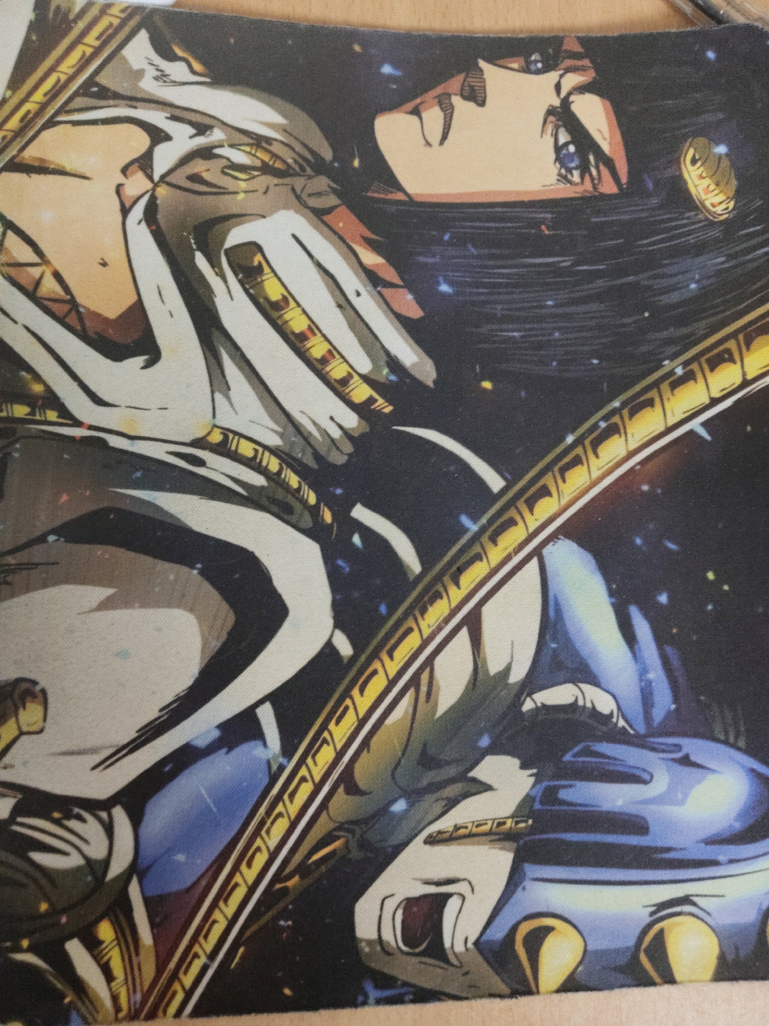 A close-up, horizontally oriented image presents an anime-style character against a dark, cosmic background. The character's head is positioned towards the upper right, featuring short, dark hair and light skin. Blue eyes are directed upwards and to the right, accompanied by a small, neutral mouth. A gold, segmented circular earring is prominently displayed on the character's right ear. The upper torso is clad in a white and grey layered garment or armor with detailed golden accents and segments. The lower portion of the character is adorned with blue armored elements. A hand, encased in blue and gold armor with two distinct golden, spherical adornments on the knuckles, is visible at the bottom right, appearing to grip a control panel or an integral part of a larger mechanism. The background is a deep, dark blue, speckled with numerous small, multicolored lights resembling stars or distant nebulae. Large, arching, golden segmented structures, similar to film strips or chains, traverse the image diagonally, acting as framing elements or components of an extensive machine. The specific location is unknown.