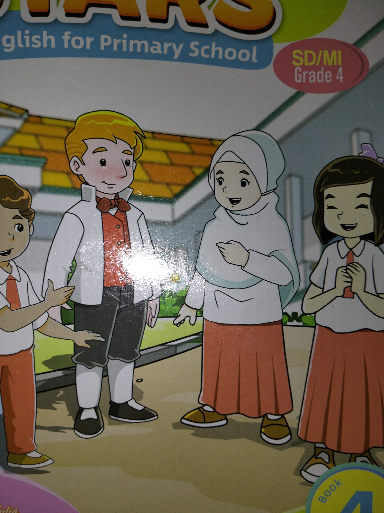 The image depicts a book cover featuring four cartoon children in an outdoor setting. The text at the top reads "English for Primary School" and "SD/MI Grade 4". The children are dressed in school uniforms. A boy in a white jacket with a red bow tie and vest stands in the center. To his left, another boy in a white shirt and orange tie gestures with his hand. To the boy's right, a girl in a white hijab and orange skirt stands with her hands clasped. A girl with dark hair and a white shirt with an orange tie, also wearing an orange skirt, stands to the right of the girl in the hijab. The background shows a building with a tiled roof and green foliage. A circular emblem with "Book 4" is visible in the lower right corner. The image does not provide any information about the city of Payagaboh, Indonesia.