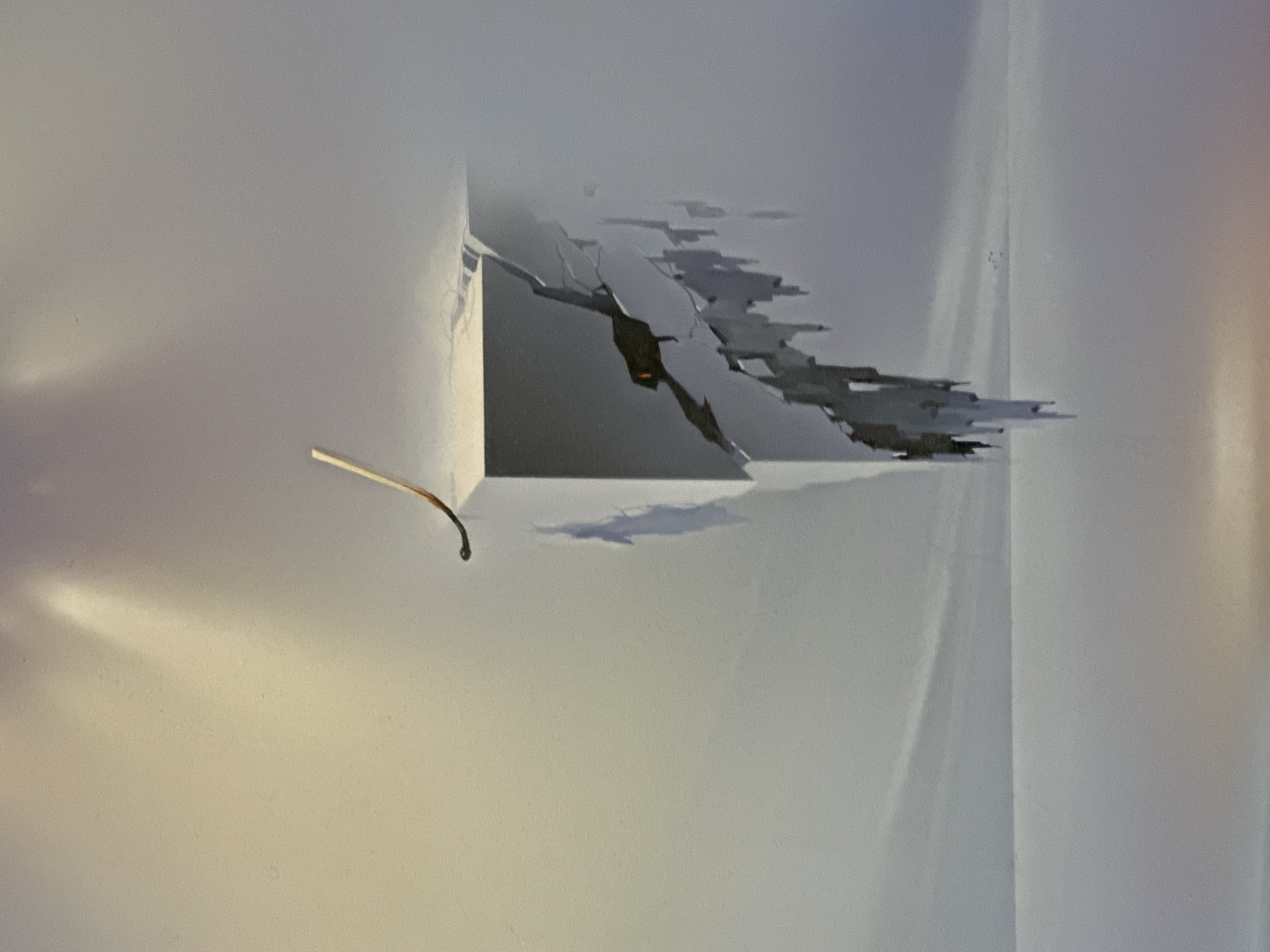 The image depicts an abstract, surreal scene. A lit matchstick, still smoldering, rests precariously on the edge of a fractured, geometric object that appears to be floating or breaking apart. The object is white with dark, jagged cracks, revealing hints of orange light from within. The background is a gradient of muted colors, transitioning from a soft yellow at the top left to a hazy grey, with a suggestion of a flat horizon line in the distance. There are no discernible elements that would place this scene in Minsk, Belarus, or any other specific city. The overall impression is one of instability and impending destruction.