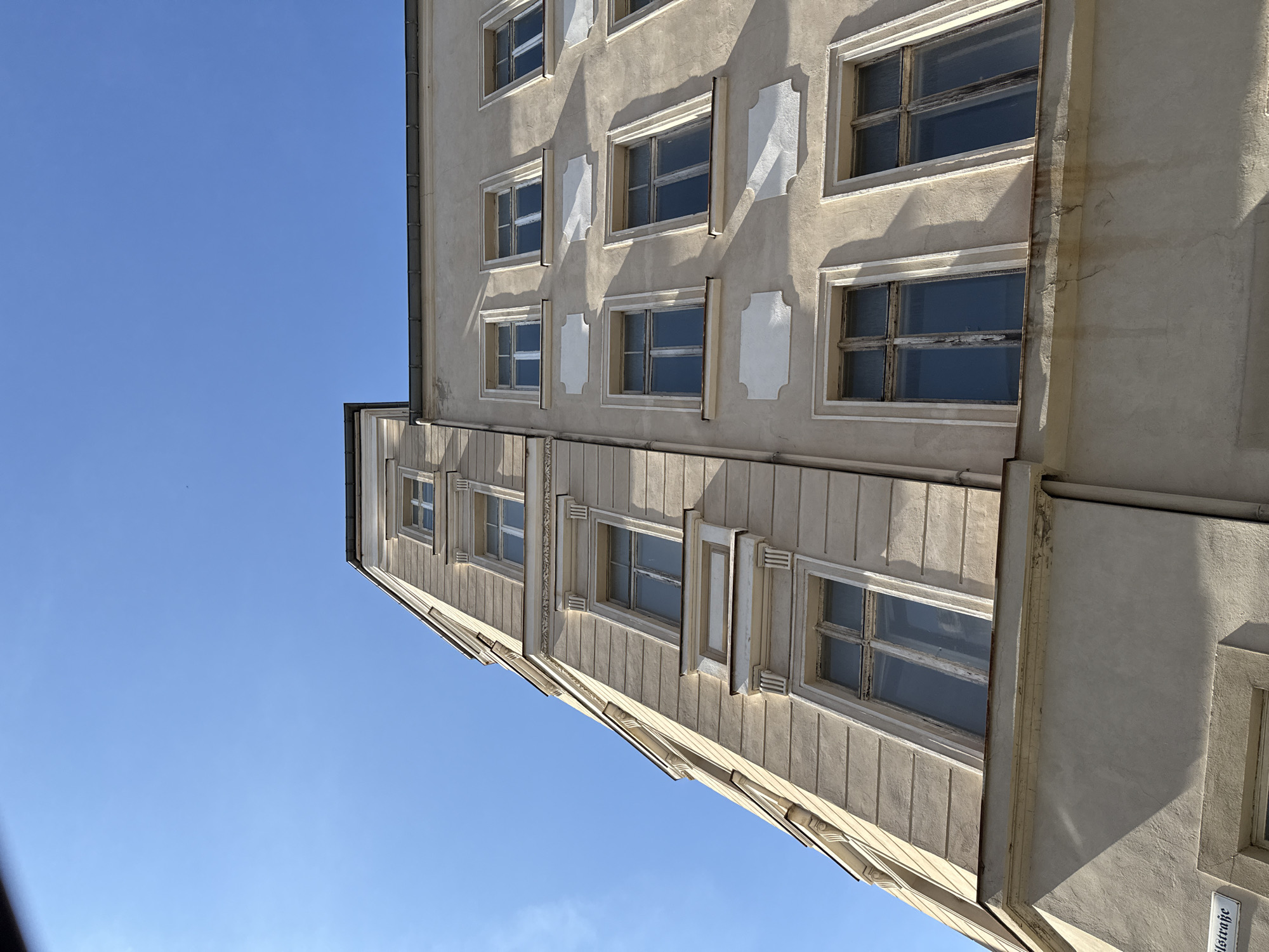 The image shows the exterior of a building in Görlitz, Germany. The building is made of light-colored stucco and has multiple stories with windows. The architectural style appears to be traditional, with decorative elements around the windows. The sky is clear and blue. A street sign that reads "Neissestrasse" is partially visible at the bottom left of the image.