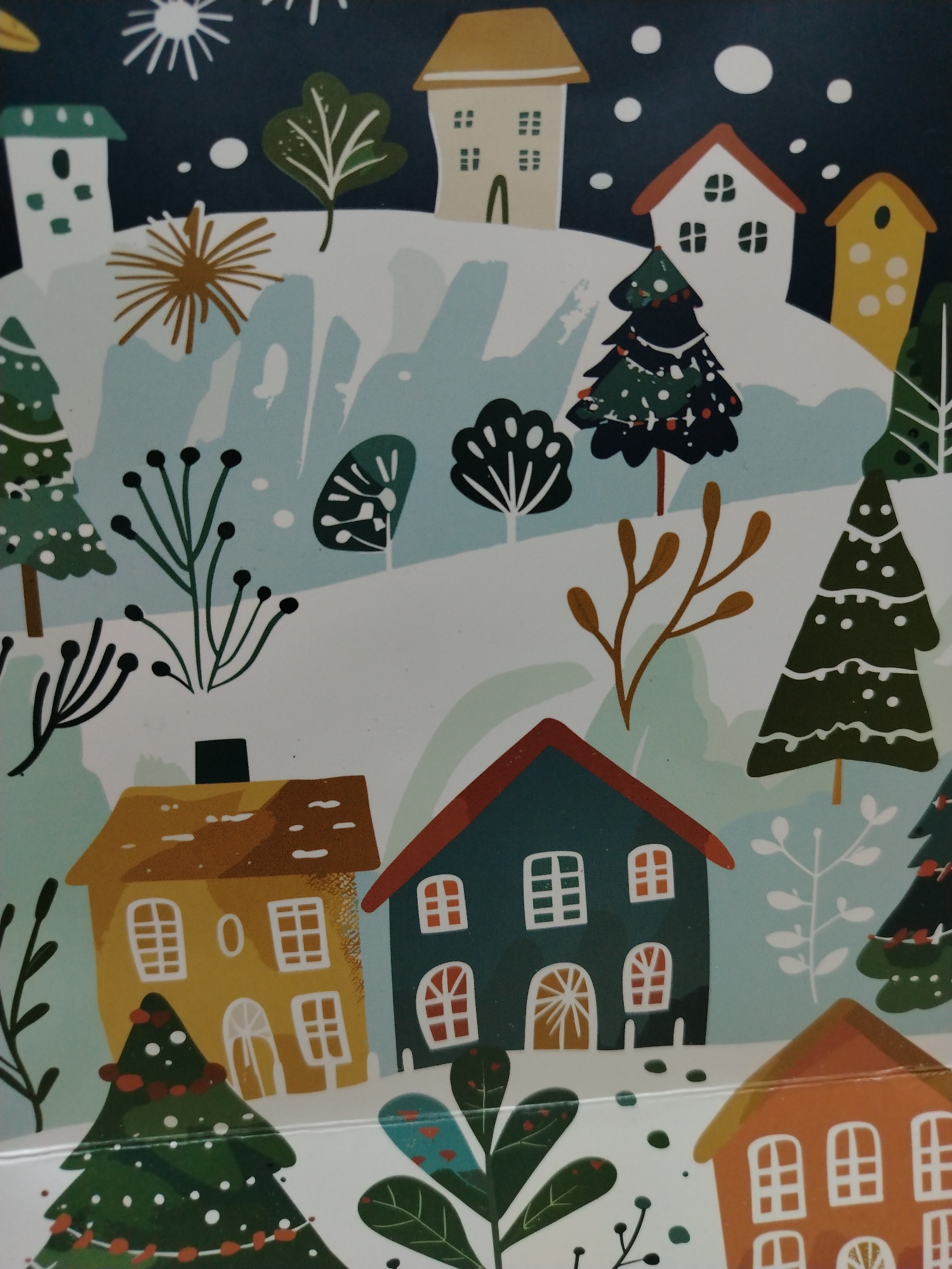 The image shows an illustration of a winter scene with houses, trees, and snow. There are several cartoonish houses with different roof colors and window designs, scattered throughout the scene. Coniferous trees, some decorated with lights or ornaments, are interspersed among the houses. The ground is covered in white, presumably snow, and the sky is dark with white dots, representing either stars or snowflakes. The style is whimsical and appears to be a festive holiday-themed graphic. There is no indication in the image that it is set in Izhevsk, Russia.