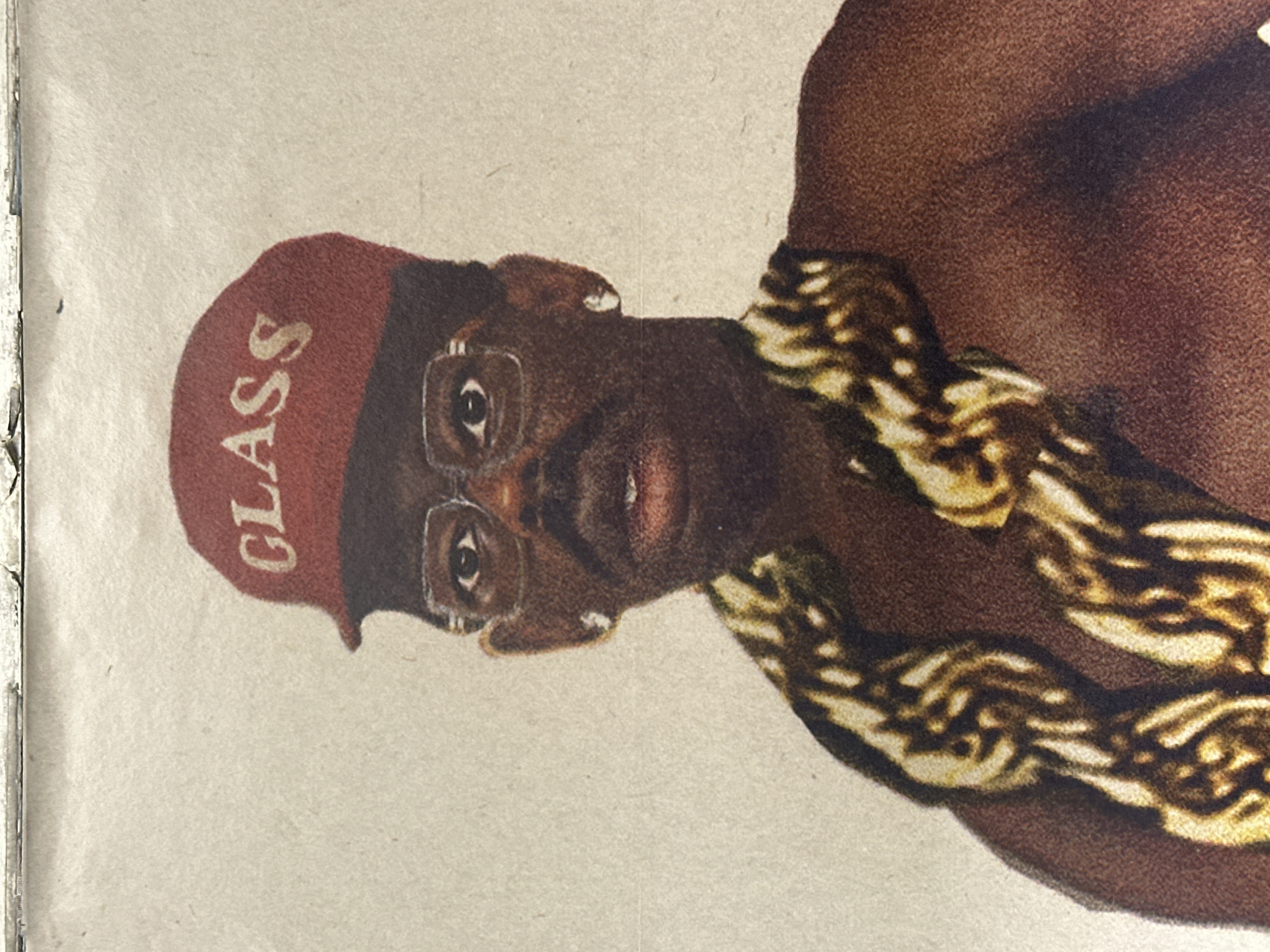 An illustration depicts a brown-skinned man with glasses and a red beret bearing the word "CLASS." He is wearing a large gold chain. The background is a neutral tan color. There is no indication of location, let alone the city of Paris, France.