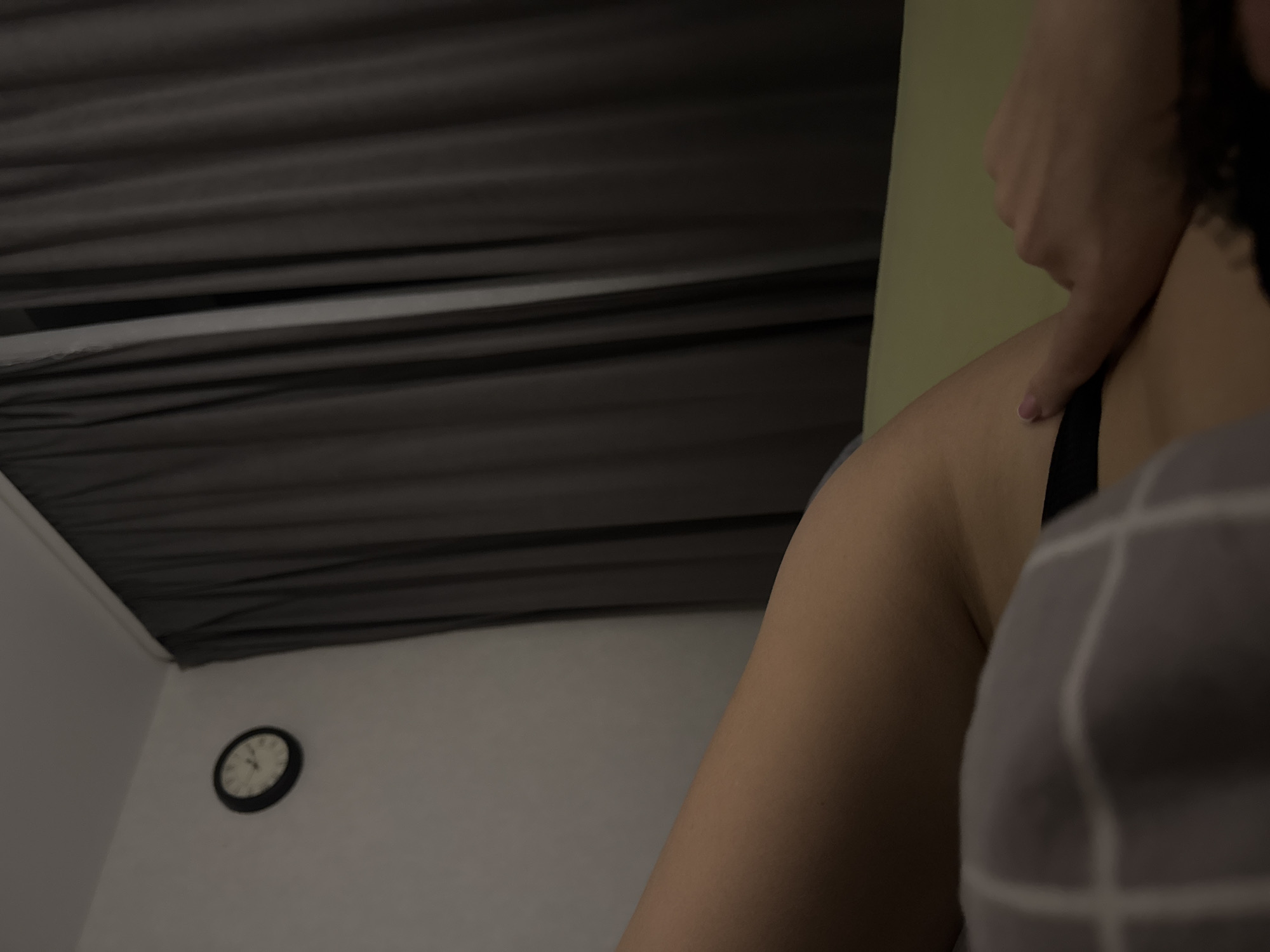 A low-angle shot of a person receiving a massage. A clock is visible on the wall, possibly taken in an indoor setting in the city of Chaikovsky, Russia.