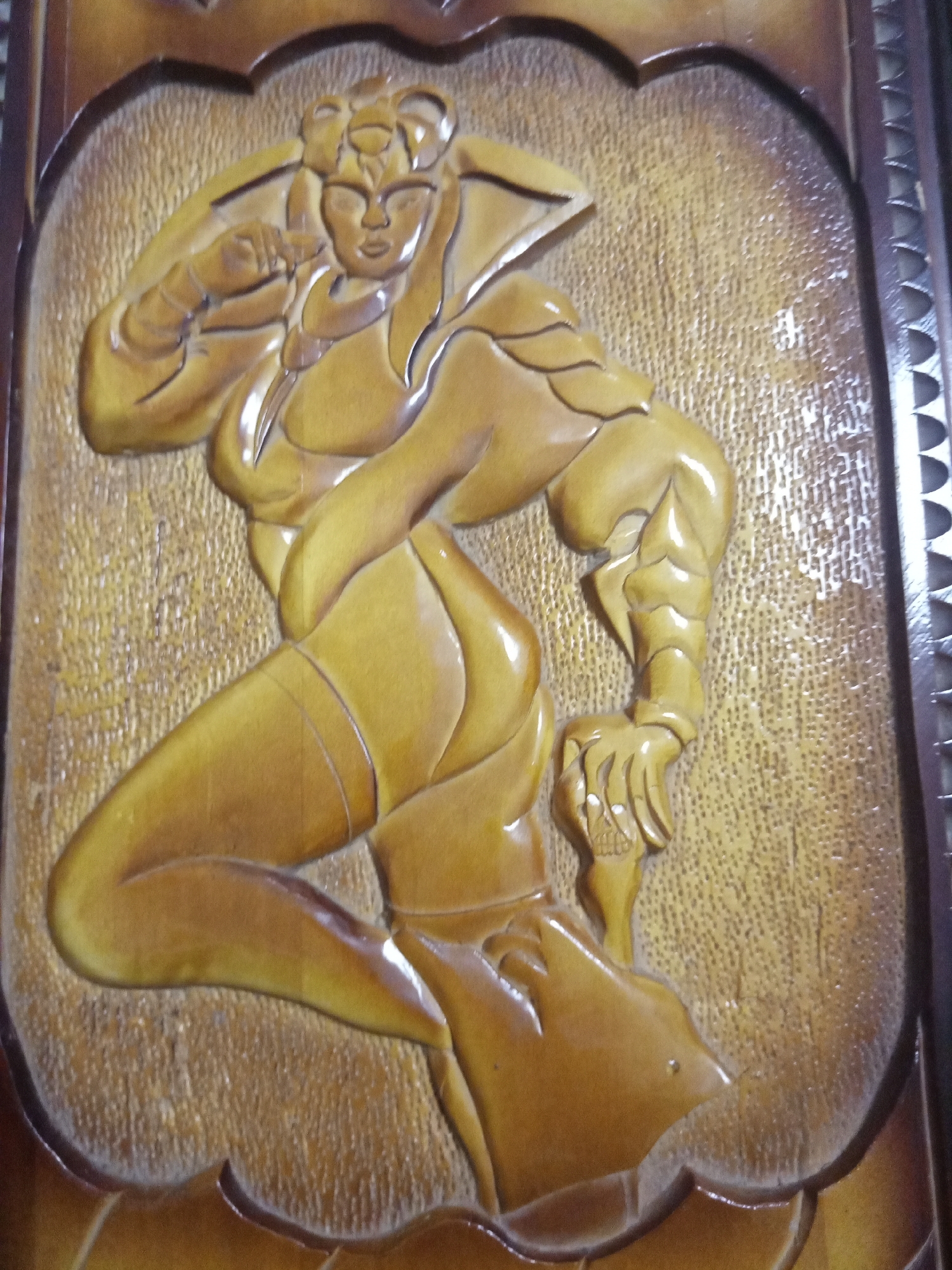The image shows a wooden carving of a woman, possibly a depiction of a fictional character, in a dynamic pose. The carving is detailed, showcasing muscular features and stylized clothing. The background of the carving has a textured surface. The carving is framed with a dark brown wooden border.
While the user requested information about the location of Elektrostal, Russia, this information cannot be provided based on the visual content of the image. There is no information in the image to indicate its location.