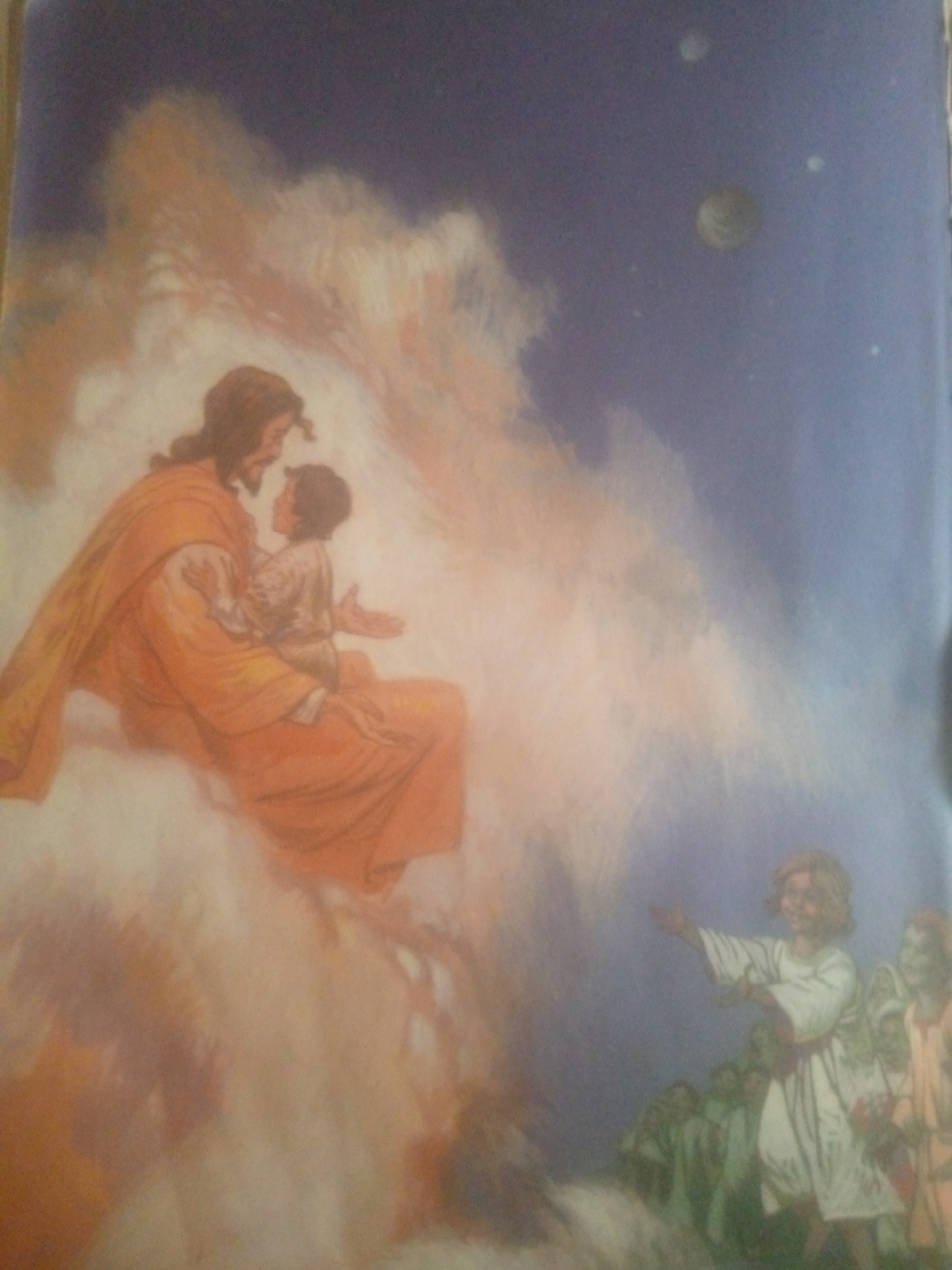 The image depicts a celestial scene with several figures. On the left, a figure resembling Jesus, with a beard and long hair, dressed in an orange robe, is holding a child. They appear to be sitting on clouds, with soft, ethereal light illuminating them. The background is a deep blue sky with faint stars and celestial bodies, including what appear to be two planets and possibly a moon.
On the right side of the image, a group of children or young figures, dressed in white robes, are gathered. One child in the foreground is smiling and reaching out with their hand. The figures are also bathed in a soft, divine light, suggesting a heavenly or spiritual setting. The overall impression is one of peace, innocence, and spiritual embrace.
The provided text does not contain any information related to the city of Jauro Yinu, Nigeria. Therefore, I cannot include any details about this location in my description.