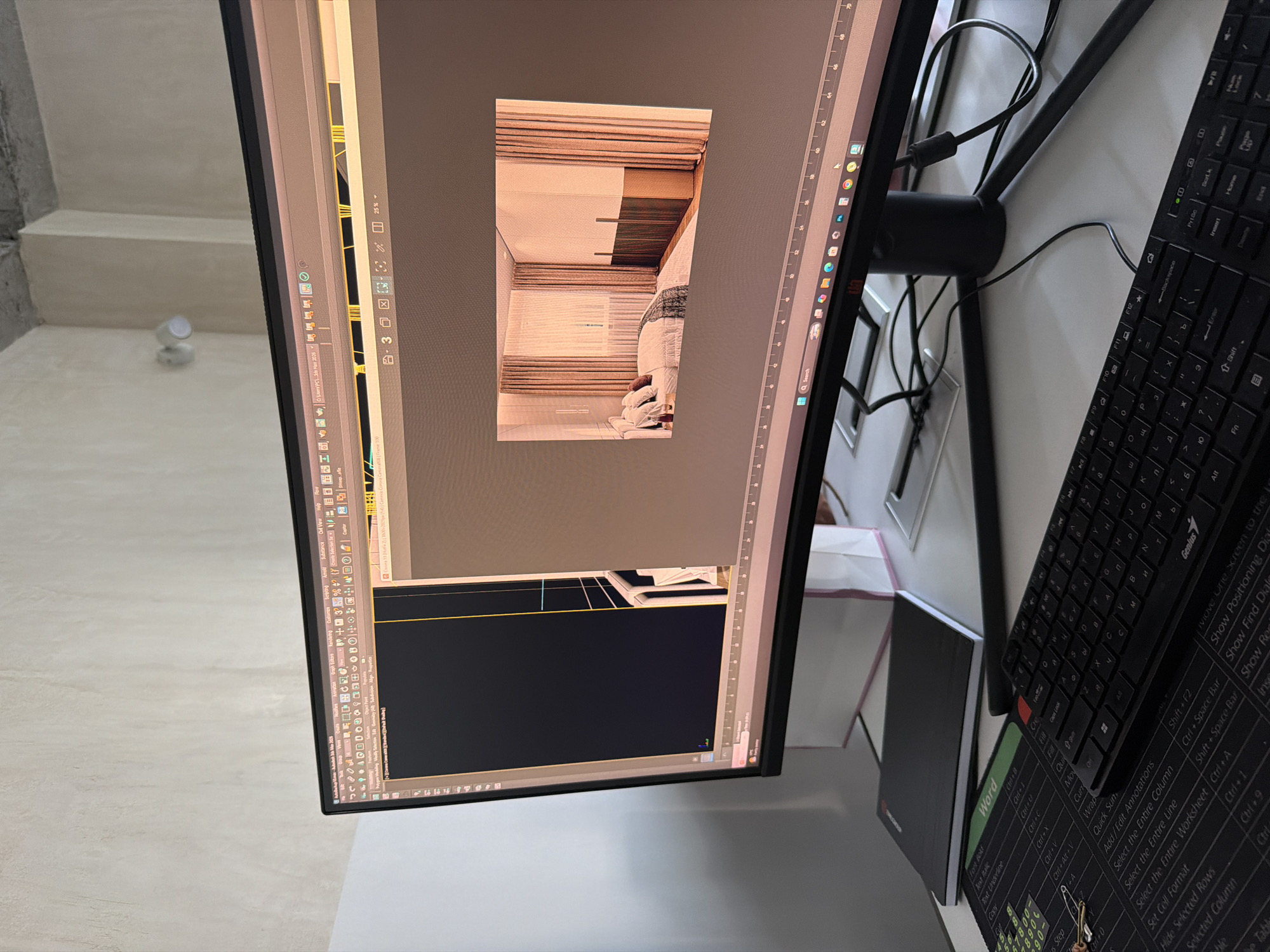 The image depicts a close-up view of a computer monitor displaying 3D rendering software, positioned on a desk. The screen shows a partially rendered interior scene, likely a bedroom, with neutral color tones and what appears to be an incomplete CAD drawing. A black keyboard and a notebook, presumably used for Word, are located on the right side of the monitor. Also a keyboard cheat sheet is seen. The exact location within Yerevan, Armenia, is not possible to determine based solely on the visual information provided.
