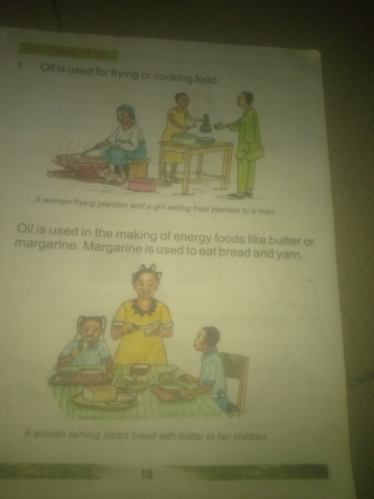 The image depicts a page from a book with illustrations and text related to the uses of oil. The top portion shows a scene with three figures. A woman is seated and appears to be cooking over a fire. To her right, a child stands by a table, and a man in a green outfit is handing something to someone out of frame. The text below this illustration reads, "A woman frying plantain and a girl selling fried plantain to a man."
Below this, more text states, "Oil is used in the making of energy foods like butter or margarine. Margarine is used to eat bread and yam." Accompanying this text is another illustration of a family scene. Two young children and a woman are gathered around a table. One child is eating from a plate, while the woman is preparing food, possibly spreading butter on bread. Another child is seated to the right. The caption for this illustration is, "A woman serving sliced bread with butter to her children."
The page is numbered "19" at the bottom. The text and illustrations are presented in a child-friendly, educational style. There is no information in the image that indicates a location in Jauro Yinu, Nigeria.