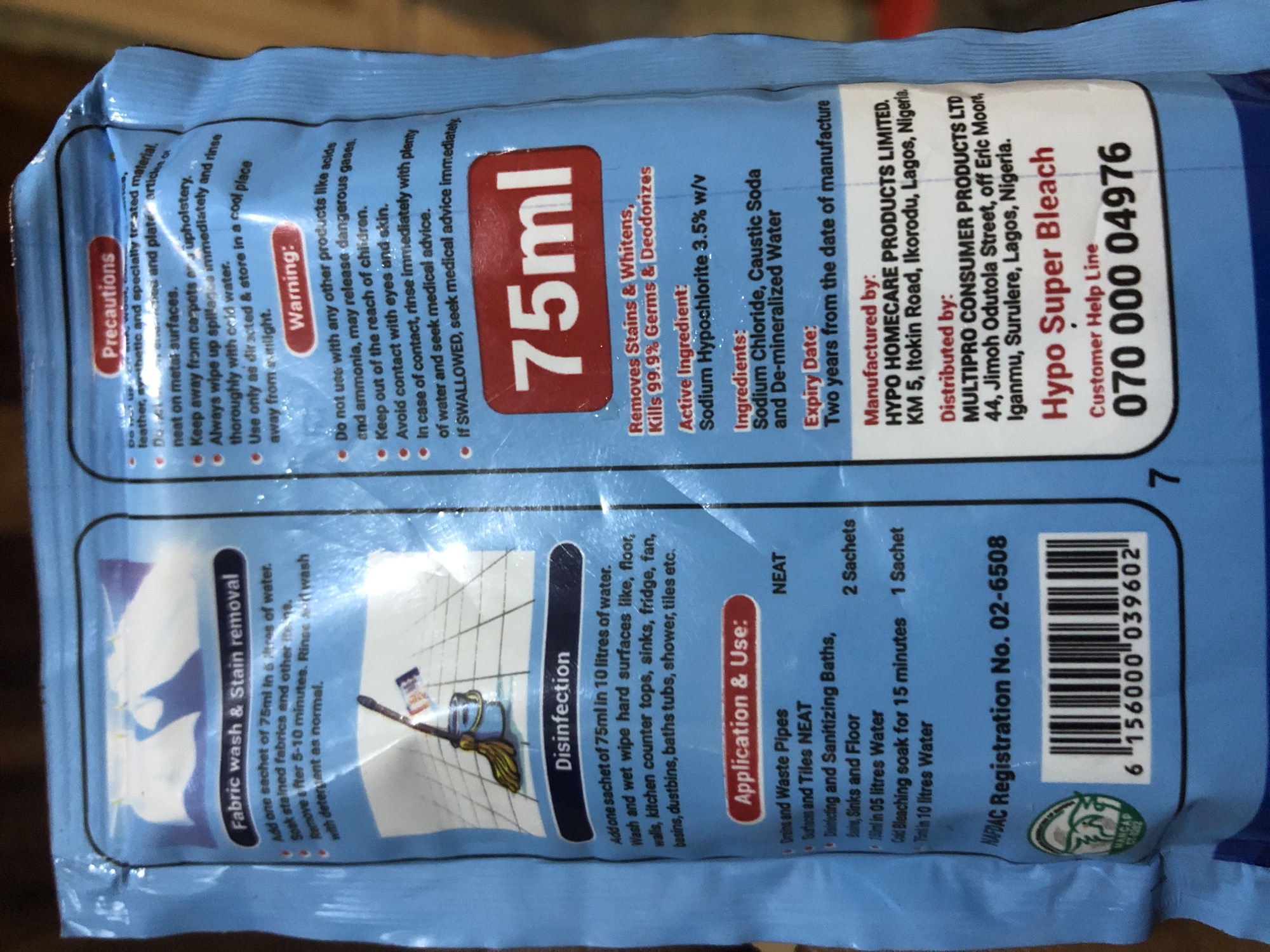 The image displays a close-up of a blue plastic sachet of Hypo Super Bleach. The sachet features various instructions and information printed in English. Prominently displayed is "75ml" in large red font. On the left side, there are instructions for "Fabric wash & Stain removal" and "Disinfection". The right side contains "Precautions" and "Warning" sections, followed by product details like "Active Ingredient," "Ingredients," and "Expiry Date." Further down, it lists "Manufactured by" and "Distributed by," including addresses in Lagos, Nigeria. The lower portion of the sachet shows a barcode and a registration number. The sachet is likely in a retail setting or a household environment. There is no information in the image that would suggest its location in Kabong, Nigeria, or any specific city.