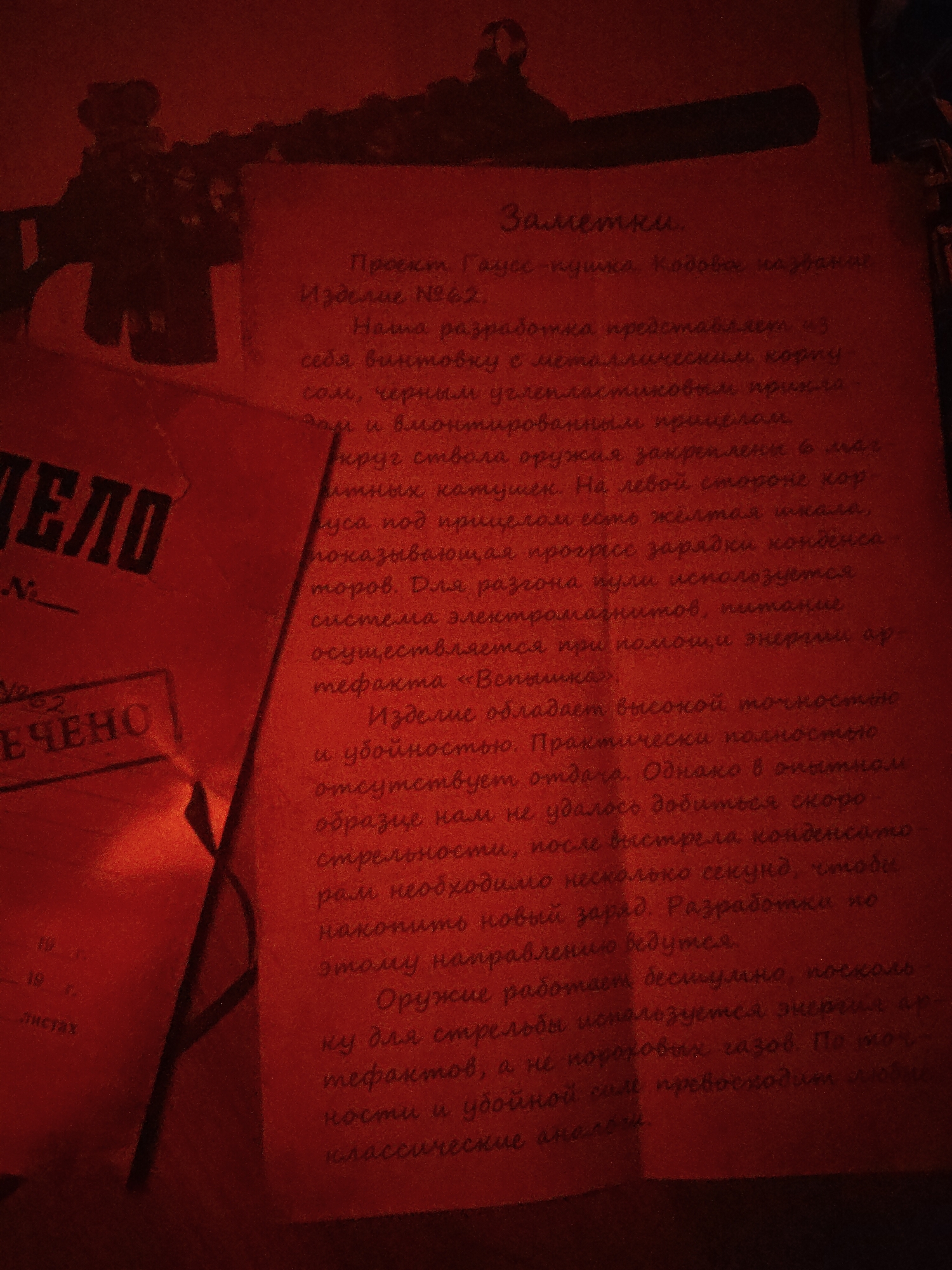 The scene is dimly lit with red light, suggesting a clandestine or emergency situation. A dark silhouette of a firearm (possibly a rifle) is visible in the upper left corner. To the right of the weapon is a red document with the heading "Заметки," meaning "Notes" in Russian. The document contains Cyrillic text outlining details of a "Gauss-пушка" (Gauss Rifle) project. The weapon is described as having a metallic body, black carbon fiber stock, and integrated sight. Magnetic coils are mounted around the barrel, and a yellow scale indicates capacitor charging progress. The system is powered by the energy of the artifact "Вспышка" (Flash). The text further discusses accuracy, stopping power, lack of recoil, and the slow rate of fire. To the left is a document with the word "ДЕЛО" (Case) and the words "Заключено" (Concluded).