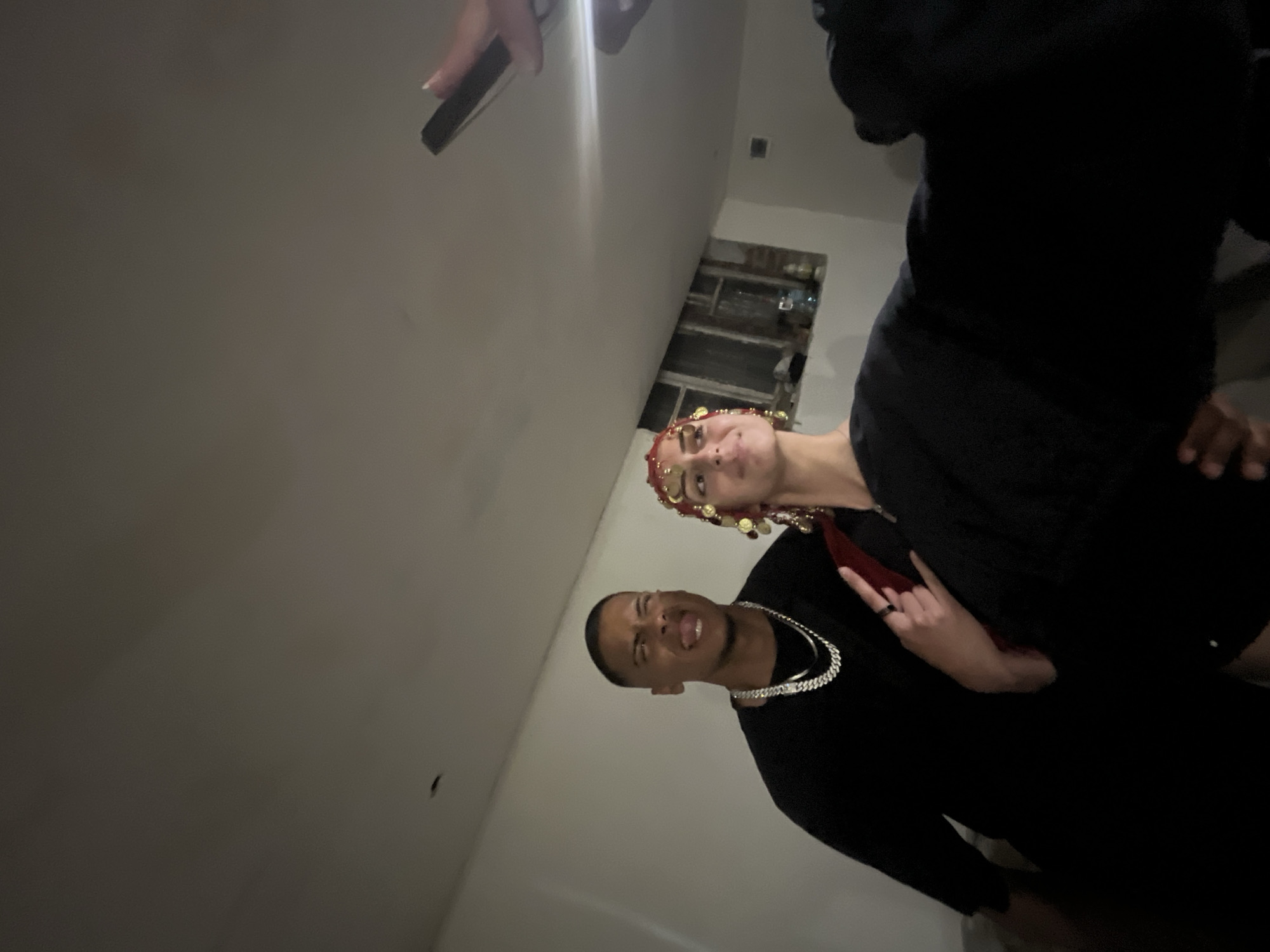 Two people are visible indoors. One person is wearing a headpiece. A man is wearing a necklace. The location is possibly Lozarevo, Bulgaria.