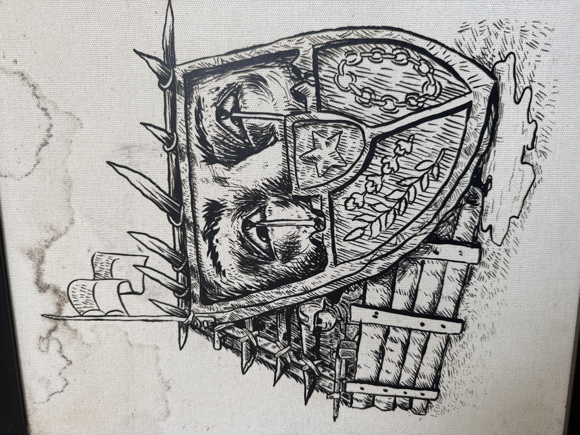 The image is a black and white ink drawing on a textured canvas that appears to be framed. The artwork depicts a fortified structure, possibly a bunker or makeshift shelter, with a prominent shield-like facade. This facade is designed to resemble a face with large, expressive eyes and a crying effect. The structure itself is built from wooden planks and is adorned with sharp, spike-like protrusions along its roofline. A soldier in a helmet, holding a rifle, is partially visible peering from behind the wooden barricade. Two flags fly from the top of the structure. The ground around the structure is rendered with cross-hatching to represent grass and dirt, with some dark, wet-looking patches at the base. The background is a pale, slightly stained canvas, suggesting a cloudy or abstract sky. There is no visible indication of any specific location in Banda Aceh, Indonesia.