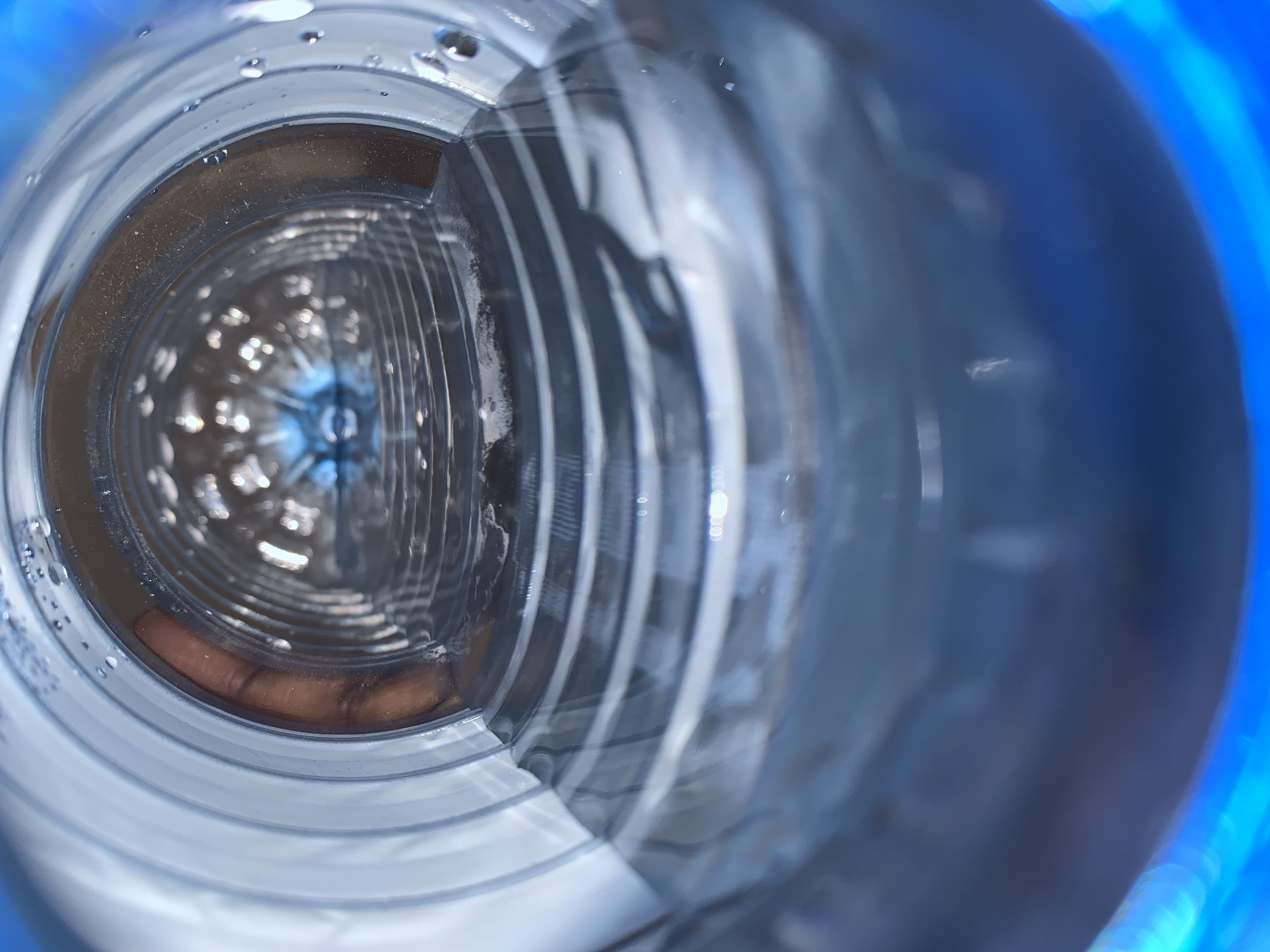 A close-up, distorted view of the inside of a plastic bottle. Reflections and refractions create patterns of light and shadow. Condensation is visible along the interior walls of the bottle. The opening appears to be at the far end, receding into the distance. No people or external environments are visible. There is no evidence to suggest the image was taken in New Stadium, Nigeria.