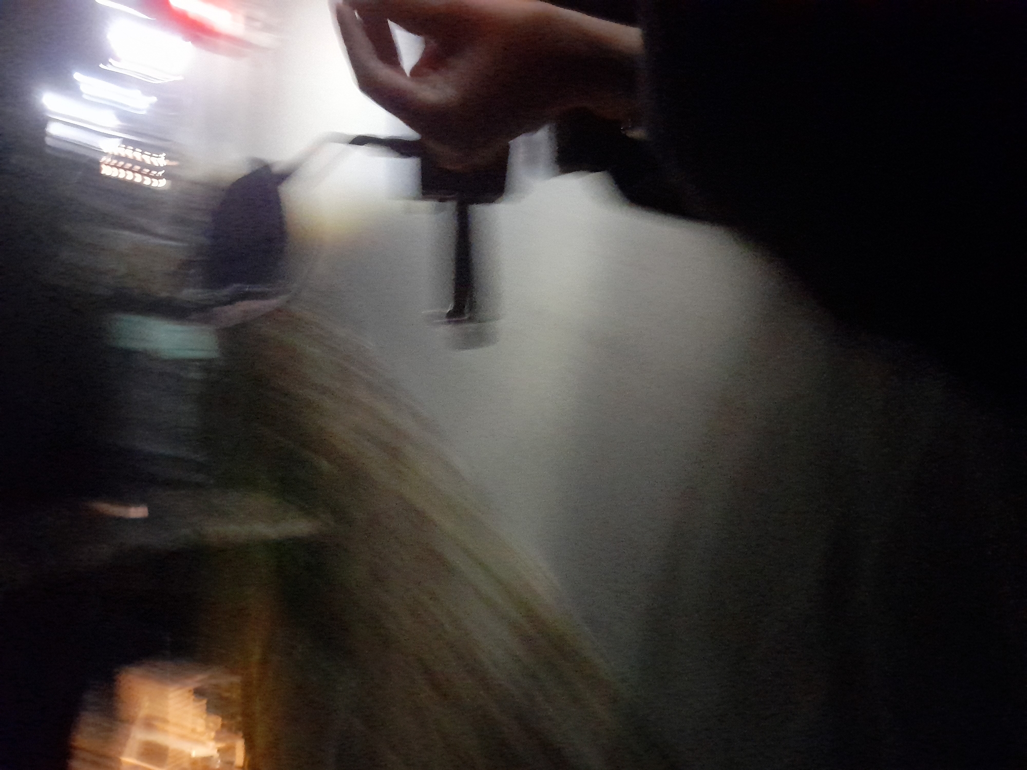 The image depicts a blurry, nighttime scene, likely captured from a moving vehicle. In the foreground, a person's hand is visible, resting on a handlebar or similar object. The background is a dark, indistinct blur of lights and shapes, suggesting an urban or semi-urban environment. The overall impression is one of motion and low visibility. The location of Jetaksari, Indonesia, is not discernible from the visual information present in the image.