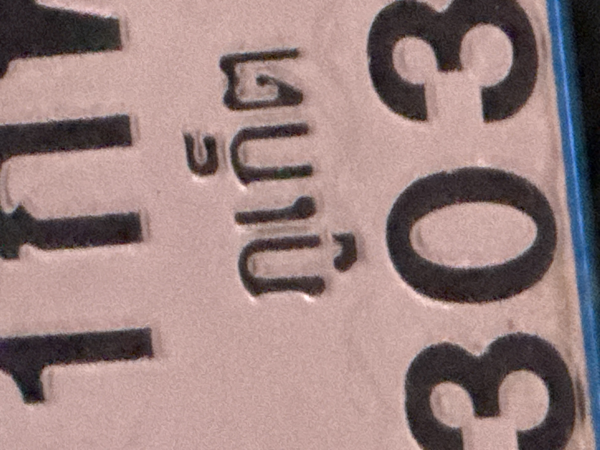 The image shows a close-up of a Thai license plate. The plate is pinkish-beige and has embossed black characters. On the left side, a portion of the characters "LL" is visible. To the right of that, a Thai phrase or word is displayed, with the characters "บ.ถ.น." followed by a small symbol above the "บ". Further to the right, the number "303" is prominently displayed, with two "3"s stacked vertically. The plate appears to be made of metal and is likely part of a vehicle. The lighting suggests it's daytime, and the setting is probably outdoors given the context of a license plate. There are no people visible in the frame.