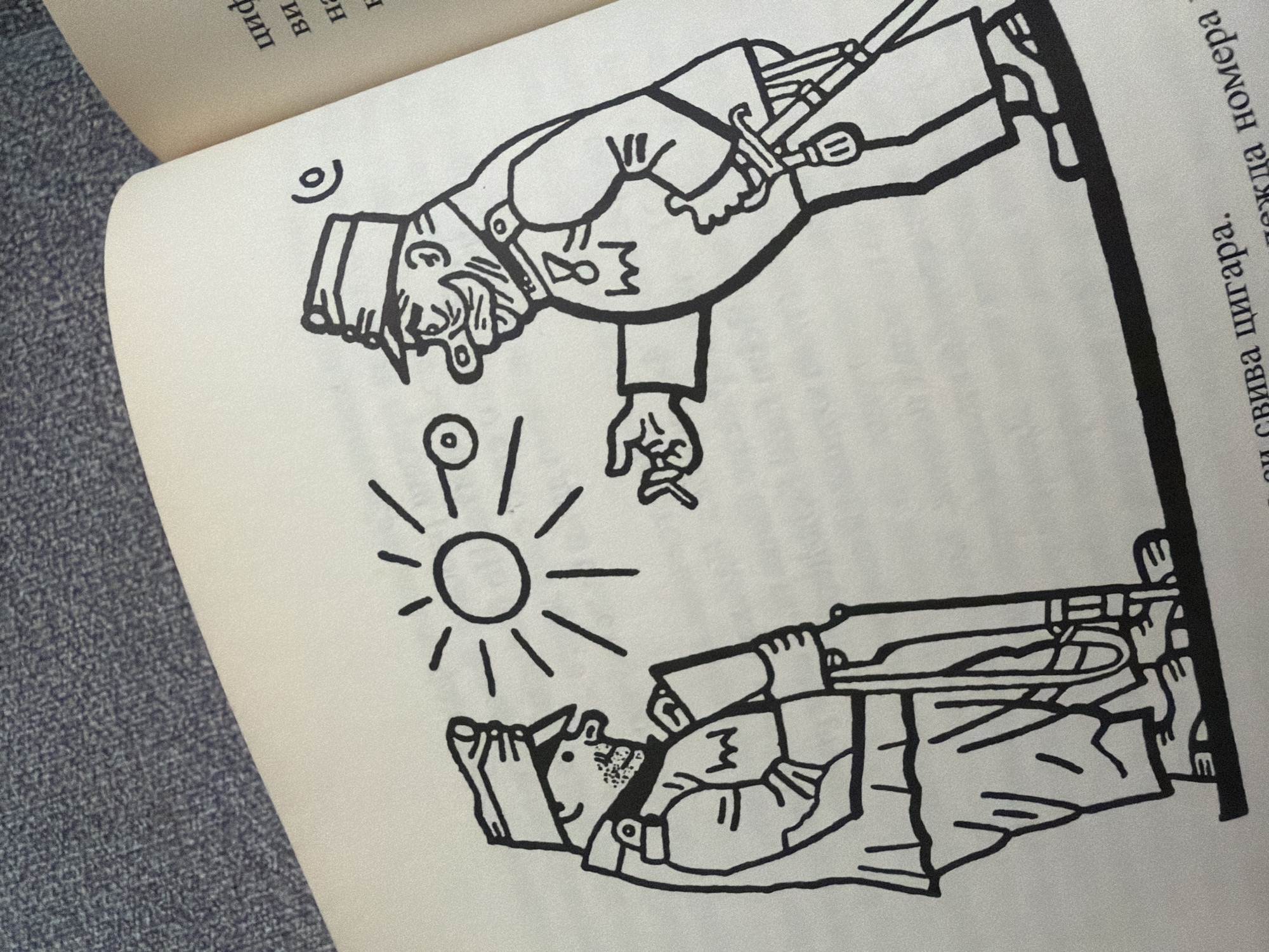 The image is a black and white ink drawing from a book, depicting two cartoon-like figures in military attire. One figure, on the left, stands with a rifle. The other figure, on the right, wears a uniform with a medal and a sword, and is offering a cigarette. Between them, a stylized sun with rays is drawn, and to its left, a circle with a line through it, resembling an eye or a button, is depicted. The drawing is on a page of a book, with text visible on the right side of the page. The background is a textured grey fabric, possibly upholstery or a surface the book is resting on. The scene is not specifically located in Pazardzhik, Bulgaria; it is a general illustration.
