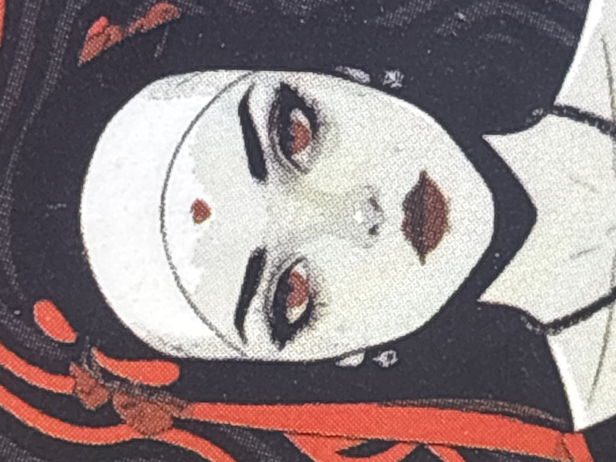 The image shows a close-up of a face with a white complexion, stylized makeup including prominent eyebrows, red-brown lips, and reddish eyes. A white head covering is also visible. A small red dot is present on the forehead. The background features black, red, and white elements, possibly indicative of clothing or a decorative pattern. Given the style of makeup and attire, it possibly depicts a representation of an Indian dancer. Without further visual clues, providing the location in Saint Petersburg, Russia is impossible.