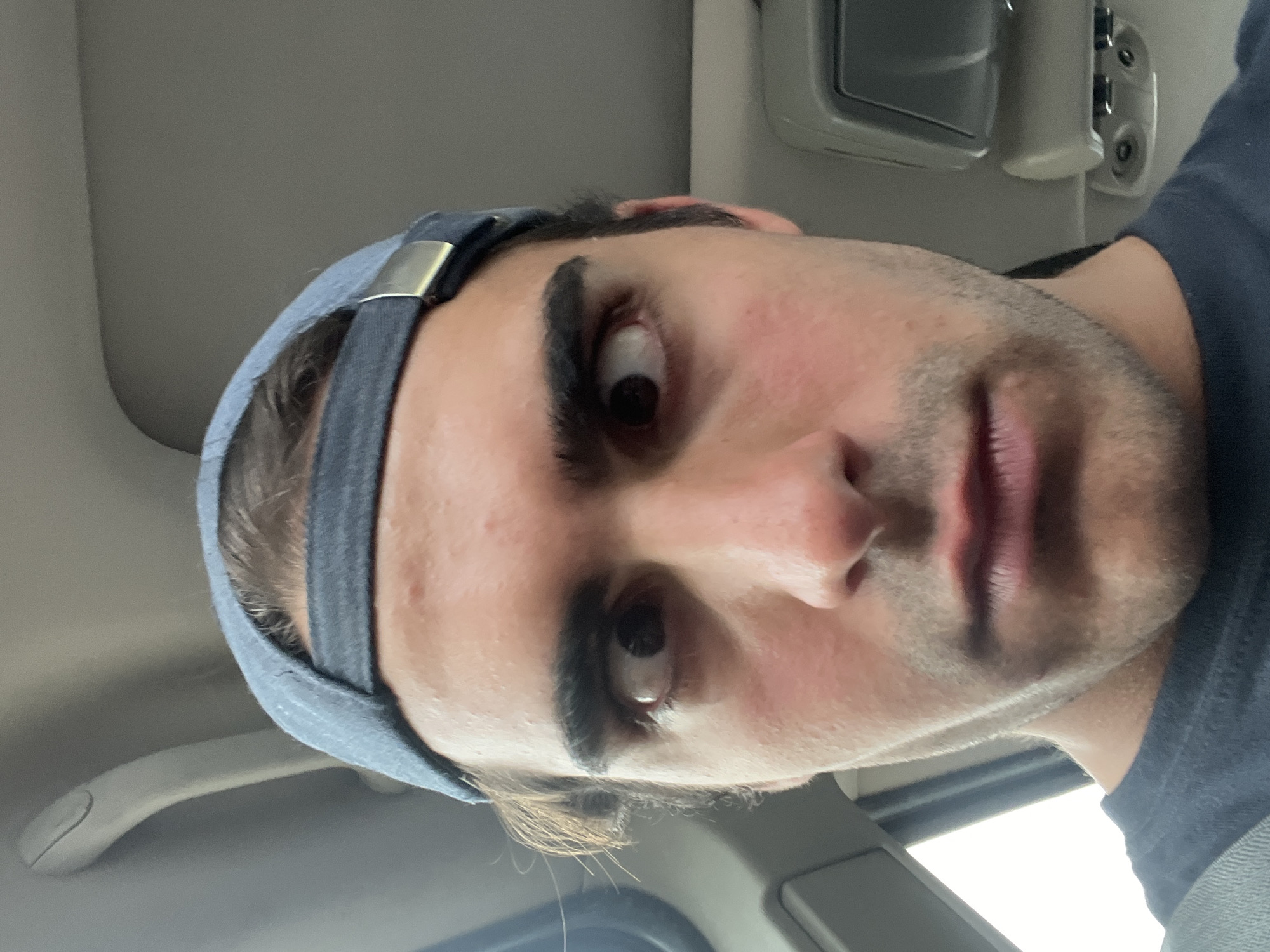 A man is inside a vehicle, possibly a car. He is wearing a blue cap. The interior of the vehicle is gray. There is a gray ceiling handle visible. The location is unknown; there is no information to determine it's Buenos Aires, Argentina.