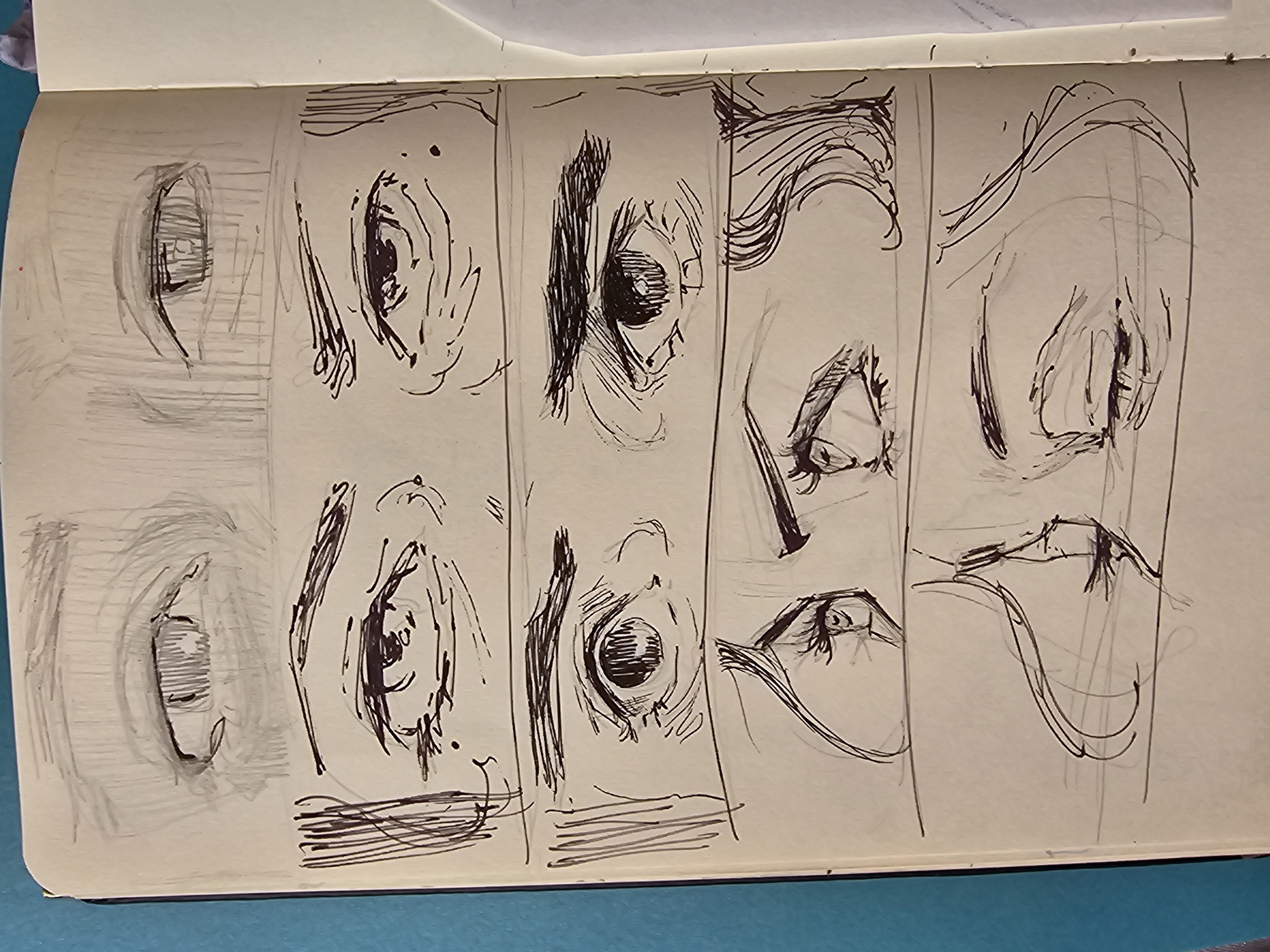 The image shows a sketchbook open on a light blue surface. The sketchbook contains several rapid sketches, primarily focused on details of the human face. From left to right, the sketches depict:
* Two stylized renderings of closed eyes.
* Two sketches of eyes with more detail, including iris and surrounding features.
* Two more detailed eye drawings with heavy hatching and strong contours.
* Two profile sketches of an eye, nose, and the suggestion of the brow line.
* Two simplified sketches suggesting the shapes of the nose and mouth area.
The background is a smooth light blue. The location is not visibly discernible from the image.