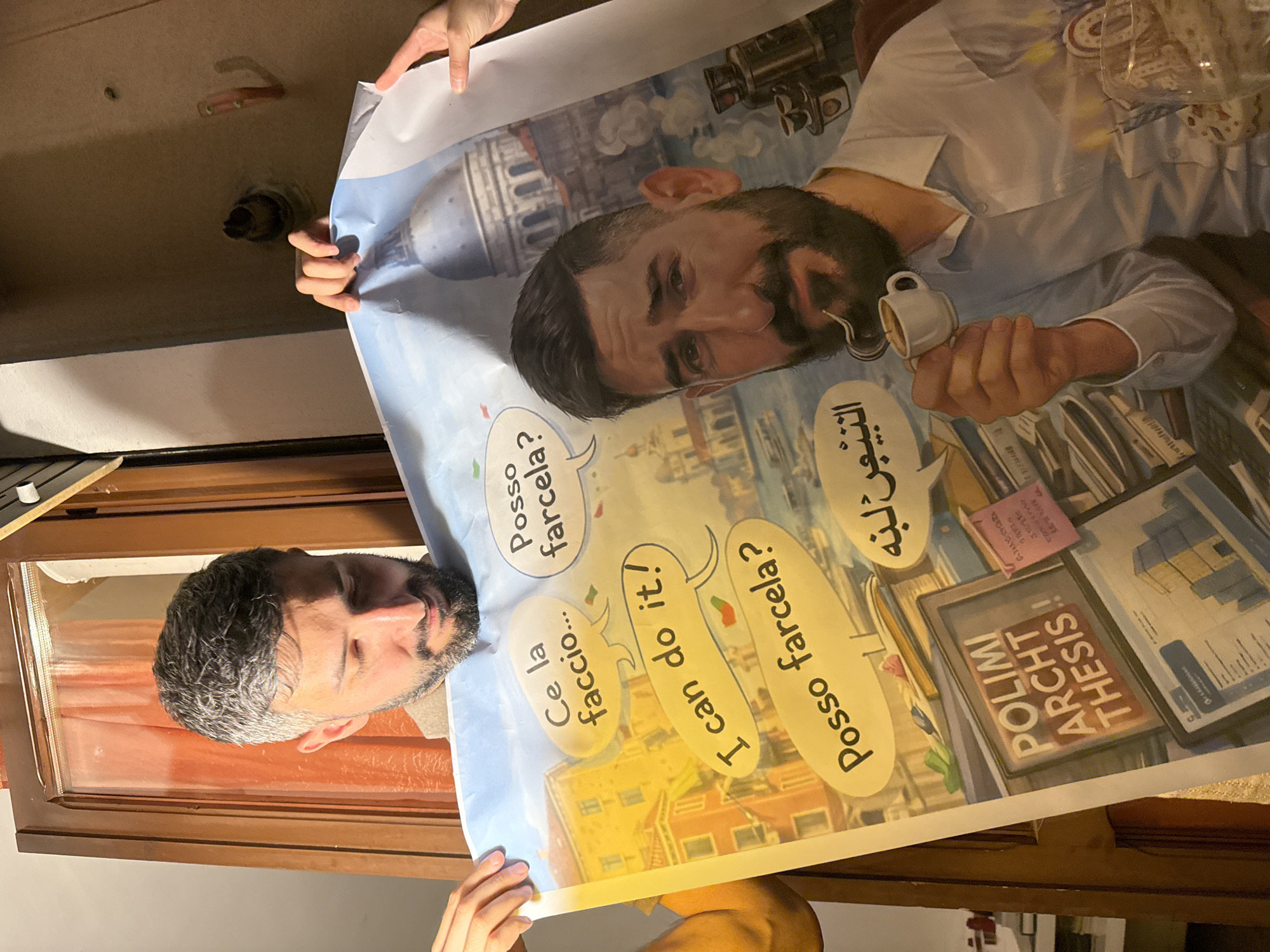 A person is holding a large, vertically oriented poster or print, obscuring most of their body except for their head at the bottom left and hands at the top and bottom. The poster features a colorful, cartoon-style illustration predominantly showing a bearded man, presumably the person holding the poster, in an urban setting. The illustrated man is wearing a light-colored shirt and holds a small white espresso cup with liquid.
The background of the illustration depicts various buildings, including a prominent domed structure reminiscent of European architecture, suggesting the location is Milan, Italy, as indicated by the context. Scattered around the illustrated man are several speech bubbles and text elements.
Visible text on the poster includes:
- Italian phrases: "Ce la faccio..." (I can do it...), "Posso farcela?" (Can I do it?).
- English phrase: "I can do it!"
- Arabic text: "النيين لبه" (as per OCR, though visually it appears to be "التخرج لي" meaning "Graduation for me").
- A prominent red and white box label reads: "POLIMI ARCHT THESIS!!", clearly indicating a "Politecnico di Milano Architecture Thesis".
Other illustrated objects on the poster include documents or architectural plans. The overall theme appears to be about the challenges and determination associated with completing an architecture thesis. The setting is indoors, likely a room with a wooden frame or window sill visible near the person's head.