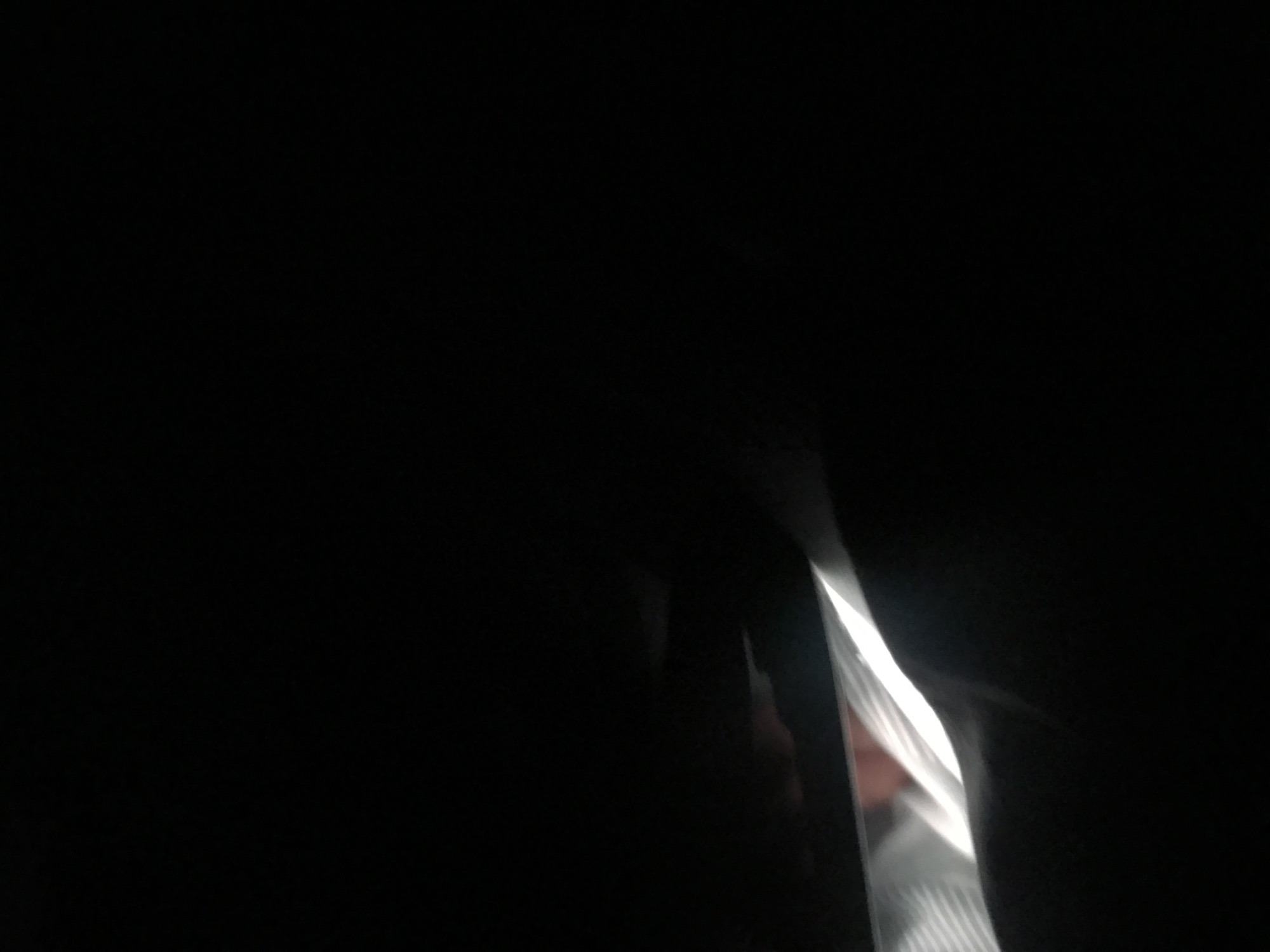 The image is very dark, making it difficult to discern details. What appears to be a sliver of light reveals a glimpse of a person wearing a striped shirt. The context of Yerevan, Armenia, is not apparent from the image. Due to the darkness and limited visibility, a comprehensive description is impossible.