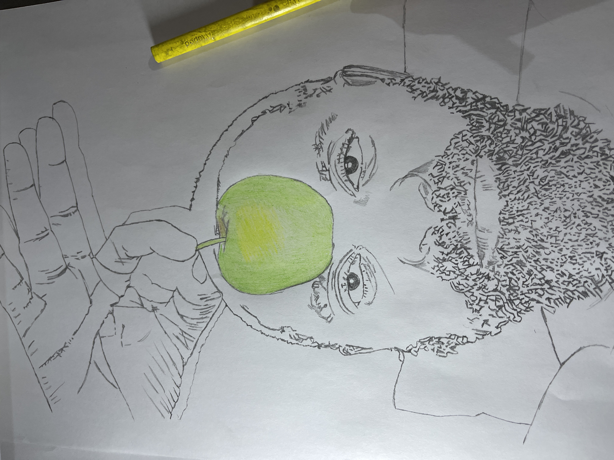A drawing on white paper depicts a person with curly hair holding a green and yellow apple in front of their face. The drawing is incomplete, with only the apple colored. The person's face is sketched in pencil, with visible eyes and facial contours. The person's hand is also sketched, holding the apple. A yellow coloring pencil rests on the paper above the drawing. The location in Jos, Nigeria, is not evident from the image.