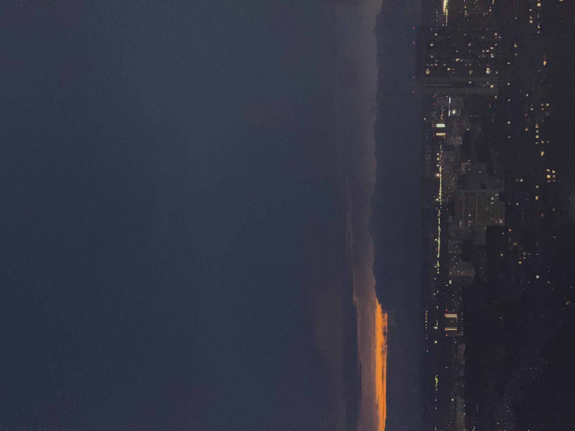 A nighttime cityscape of Гамово, Russia, shows an orange glow along the horizon. The buildings and street lights are visible on the right side of the image. The sky is dark, and the weather is overcast.