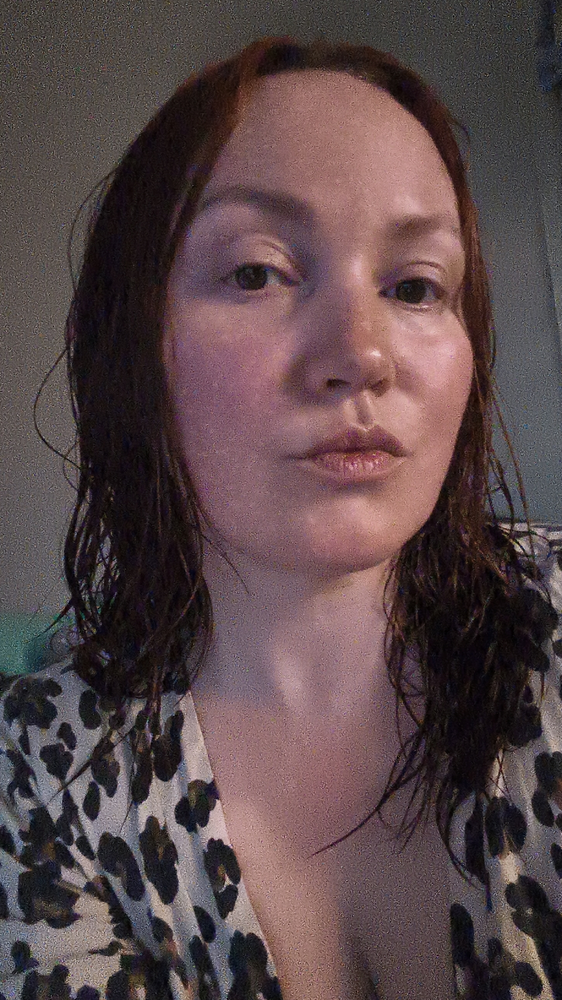 A close-up, slightly off-center shot depicts a fair-skinned woman with wet, auburn hair. She is wearing a low-cut blouse with a leopard print pattern. Her expression is neutral with slightly pursed lips. The background is blurry and indistinct. There is no information to suggest this image was taken in Chaikovsky, Russia.