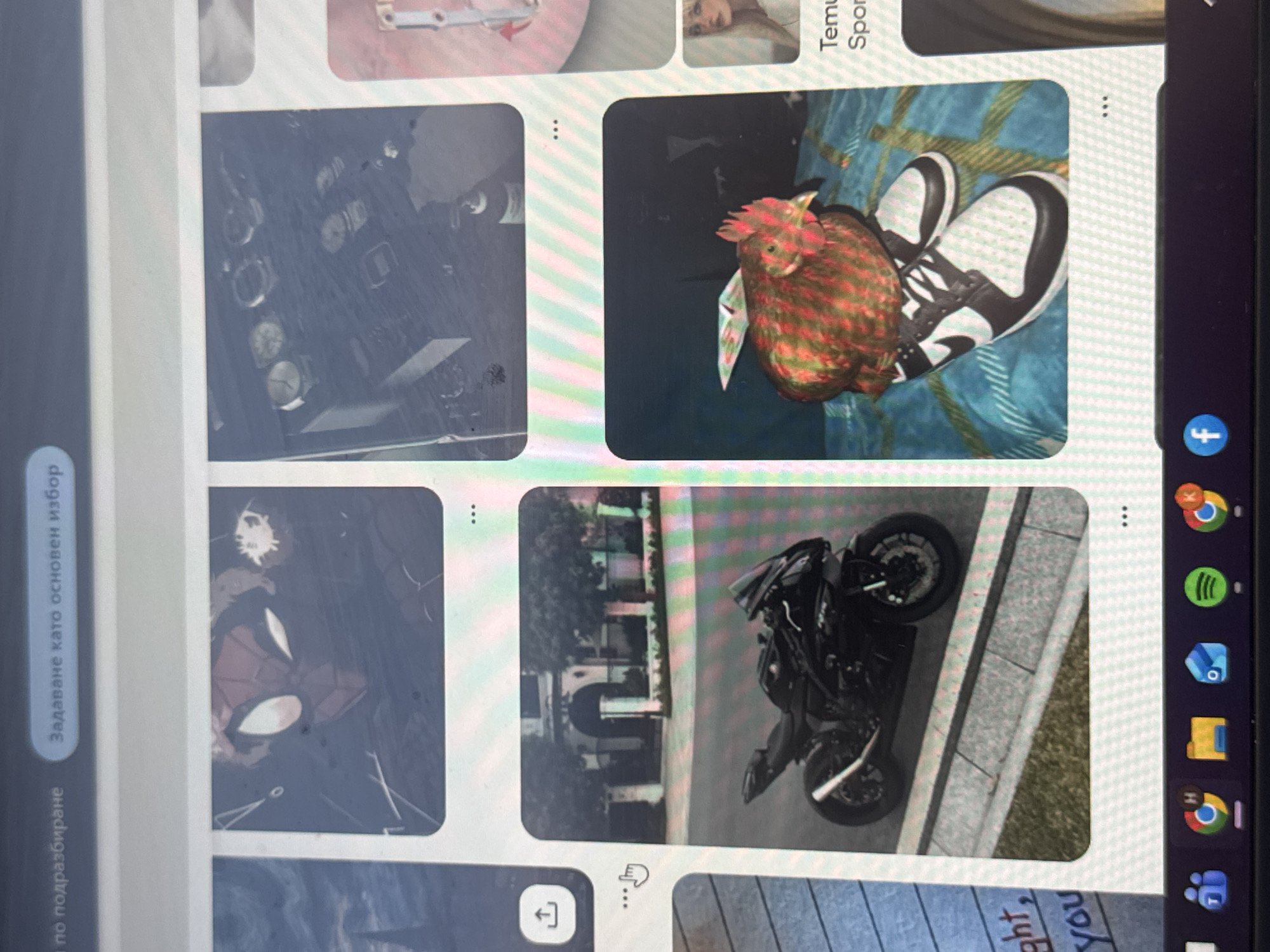 The image displays a vertically oriented computer screen, likely a laptop or tablet, showing an image-browsing interface, possibly Pinterest, in Varna, Bulgaria. The screen presents several image tiles and user interface elements.
In the main content area, four prominent image tiles are visible. The top-left tile features a collection of wristwatches arranged on a dark surface. The top-right tile shows a colorful, red, green, and gold-patterned chicken standing on a person's feet, which are clad in black and white sneakers (resembling Nike Dunks) on a blue and green patterned blanket or rug. The bottom-left tile displays a close-up, partial view of Spider-Man's masked face. The bottom-right tile shows a black sports motorcycle parked on a paved sidewalk next to a building, which appears to have an arched entrance.
To the left of the main image display, a sidebar contains two buttons with Bulgarian text. The upper button reads "Задаване като основен избор" (Set as main choice), and the lower one says "по подразбиране" (by default). A human finger is visible, pointing at a hand-pointing cursor icon near the bottom-center of the screen.
On the right side of the screen, a vertical taskbar or dock displays several application icons, including Facebook, Google Chrome, Spotify, Microsoft Outlook/Office, a folder icon, and Microsoft Teams. Smaller, partially visible image tiles also show fragments of text like "Temu," "Spor," and "ght, you." Three-dot menu icons are present on most image tiles, indicating options for each. The scene captures the act of browsing visual content on a digital device.