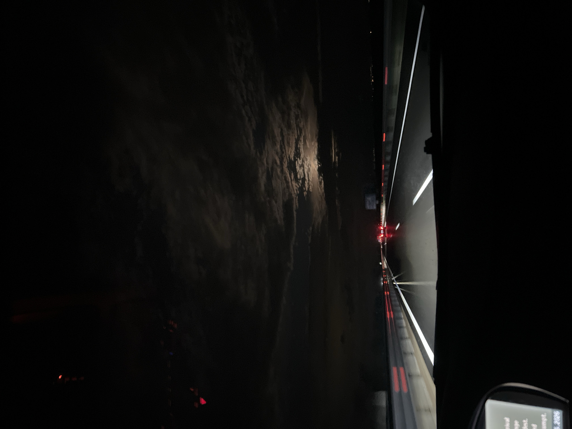 The image shows a nighttime scene from the interior of a vehicle, likely a car, traveling on a highway. There is a view of the road ahead, illuminated by the vehicle's headlights and the taillights of other vehicles in the distance. The sky is dark with visible clouds. The location appears to be Saraia, Bulgaria, although the image does not offer any evidence to confirm this. A navigation device is also visible in the lower right corner of the frame.