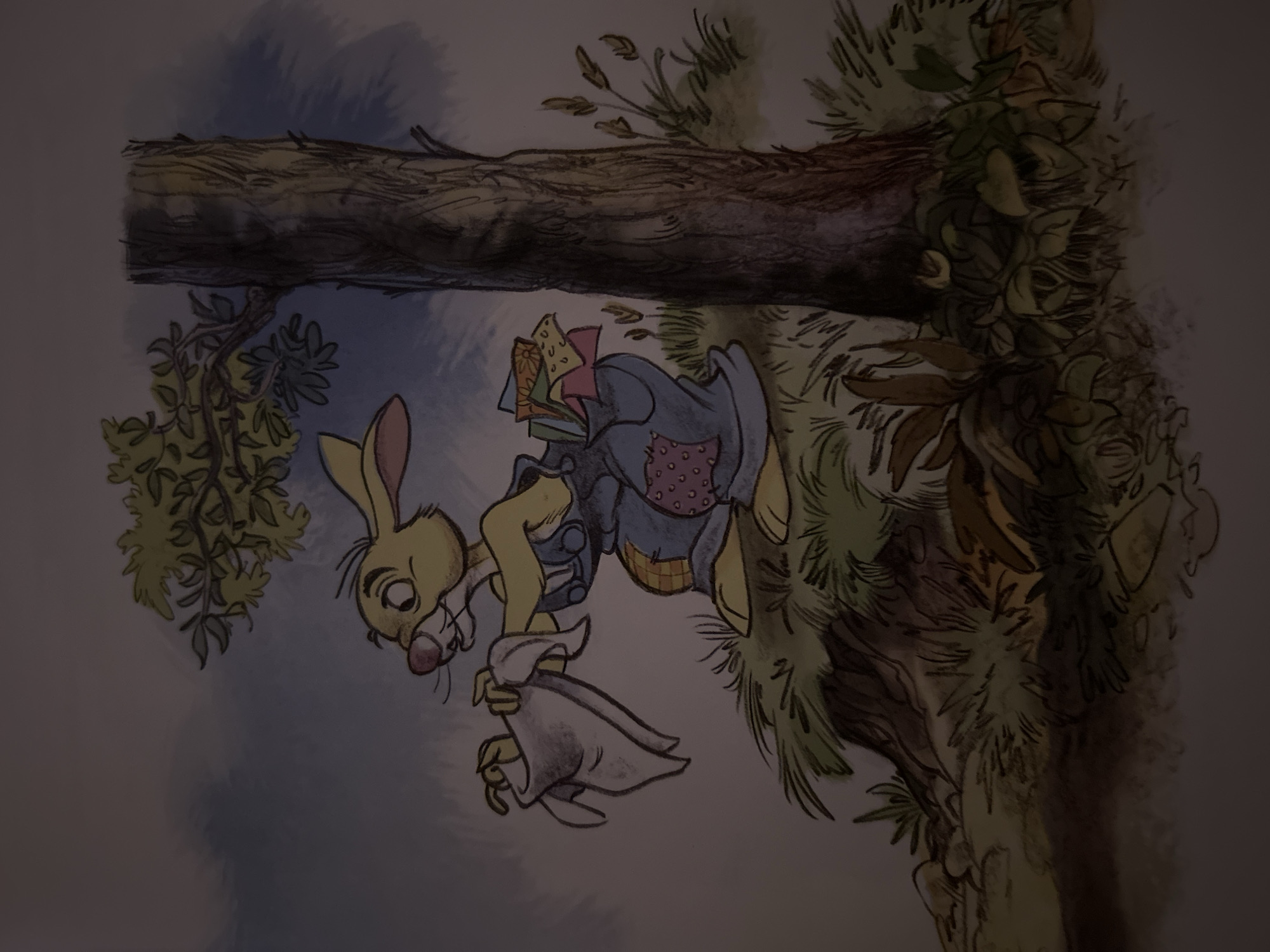 This is a watercolor and ink illustration of a cartoon rabbit. The rabbit is yellow with pink inside its ears and a pink nose. It is wearing blue overalls with a patchwork design on the legs, featuring a square of yellow fabric with orange flowers, a square of purple fabric with pink dots, and a square of blue fabric with yellow and green shapes. The rabbit is standing on a grassy knoll next to a large tree with rough bark. Its left arm is raised, holding a white cloth or handkerchief. Its right arm is bent, and its hand is tucked into its overall pocket, from which colorful folded papers or fabric scraps are protruding. The background depicts a cloudy sky and a leafy branch extending from the tree. The overall style is illustrative and appears to be from a children's book. There is no discernible connection to the city of Sofia, Bulgaria.