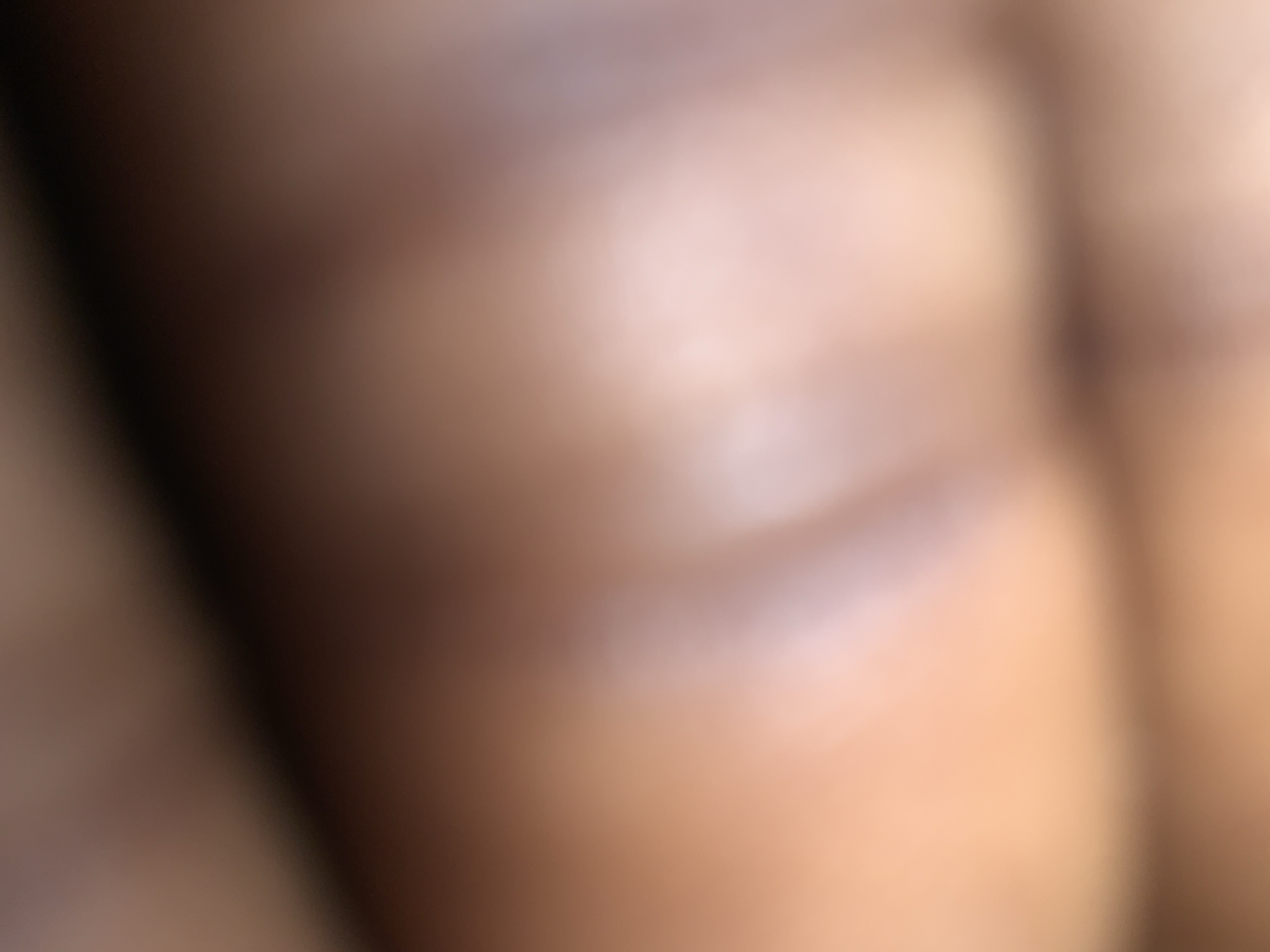 The image is a close-up, abstract photograph characterized by soft focus and a warm, diffused light. The dominant colors are shades of brown, beige, and pink, blending into one another without clear definition. There are no discernible objects, people, or environmental features that allow for identification of a specific location, including the city of Jalingo, Nigeria. The image appears to be a macro shot of a textured surface, possibly skin or fabric, with subtle variations in light and shadow creating a sense of depth and form.