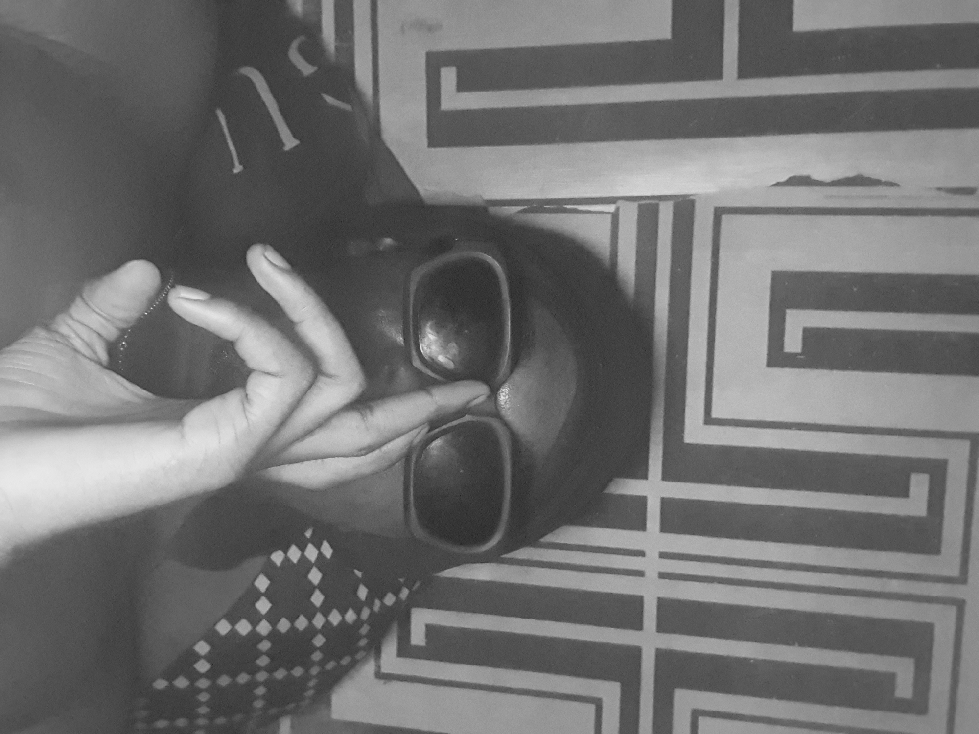A person wearing sunglasses is lying on a patterned surface. The person's hand is near their face. The surface has a geometric pattern of black and white lines. The location in Lokoja, Nigeria, is not determinable from this image.