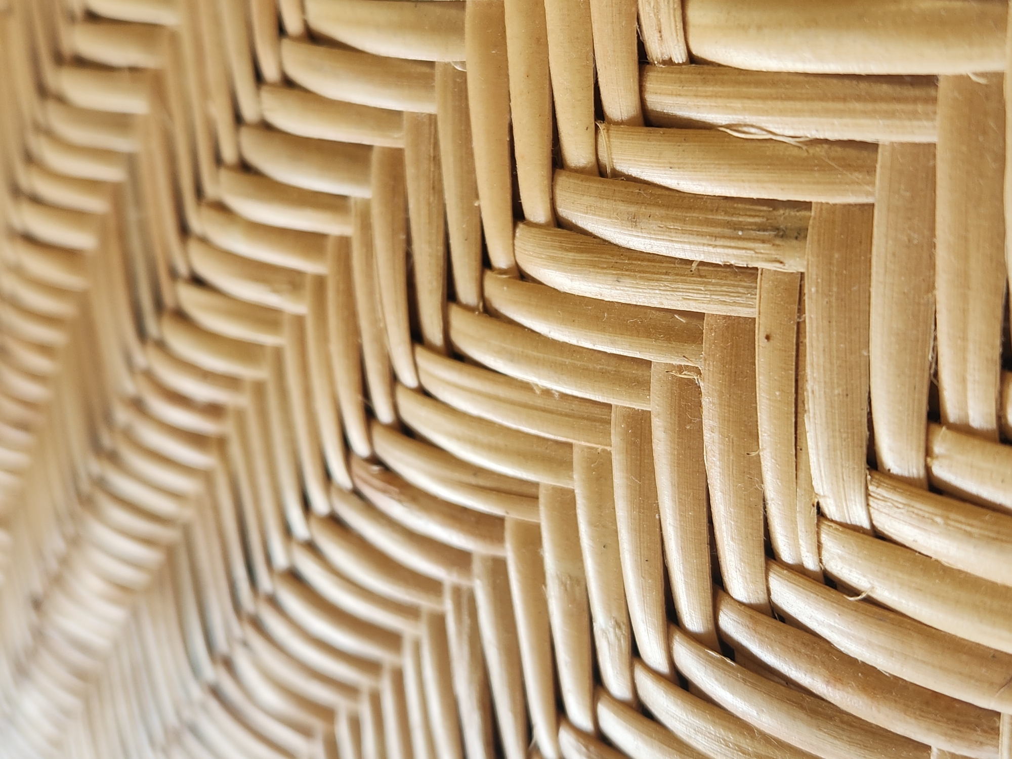 The image is a close-up, abstract shot of a woven wicker or rattan material, possibly from a piece of furniture. The texture is characterized by the interlocking strands of light brown material, creating a repeating diagonal pattern. There are no people, identifiable landmarks, or specific environmental features visible that would allow for a location within Maitland, United States of America to be determined. The focus is entirely on the material's texture and weave.