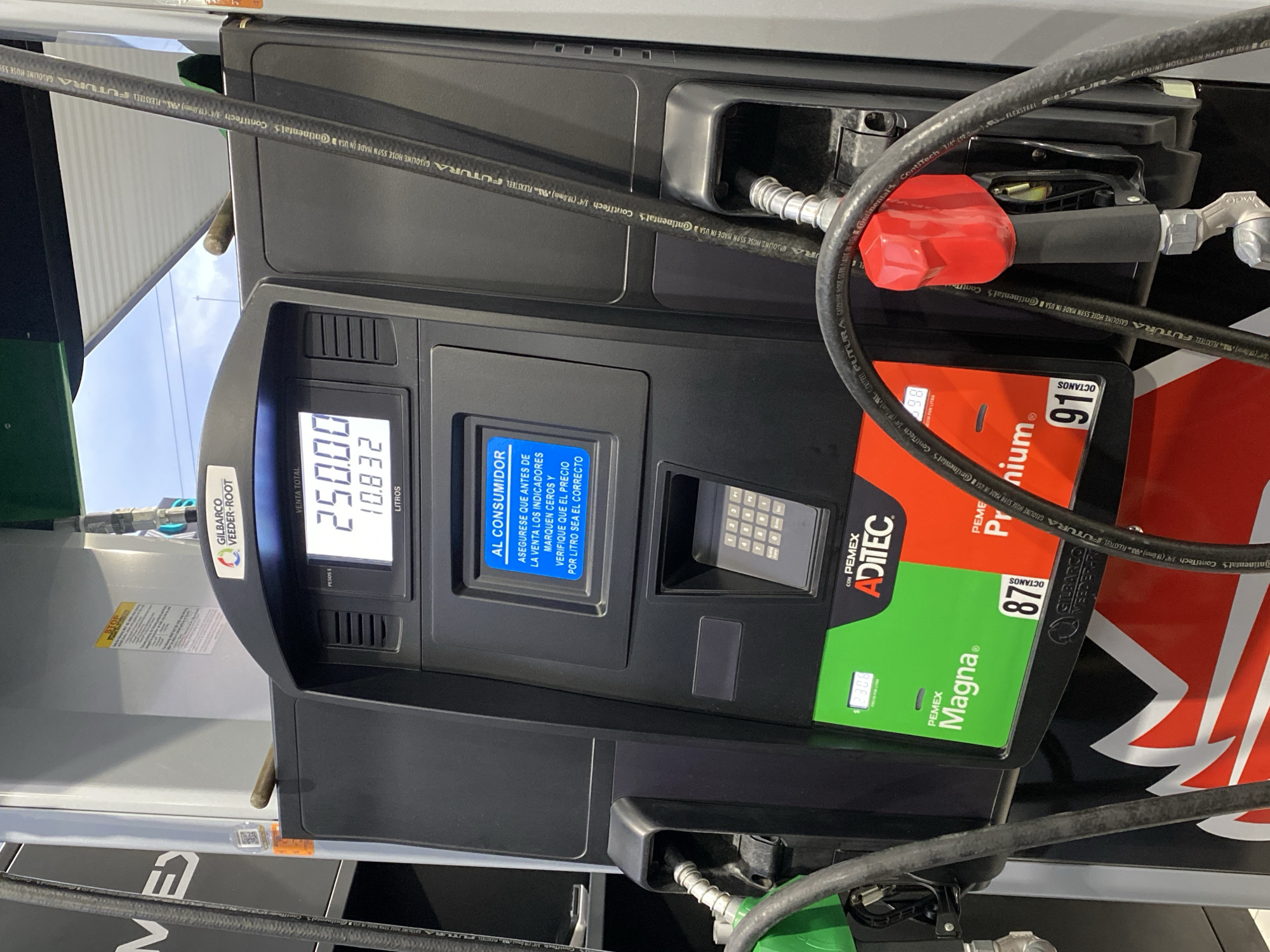 The image shows a gas pump at a Pemex station in Puebla, Mexico. The display shows a total sale of 250 pesos and 10.832 liters. The pump offers Magna and Premium gasoline.